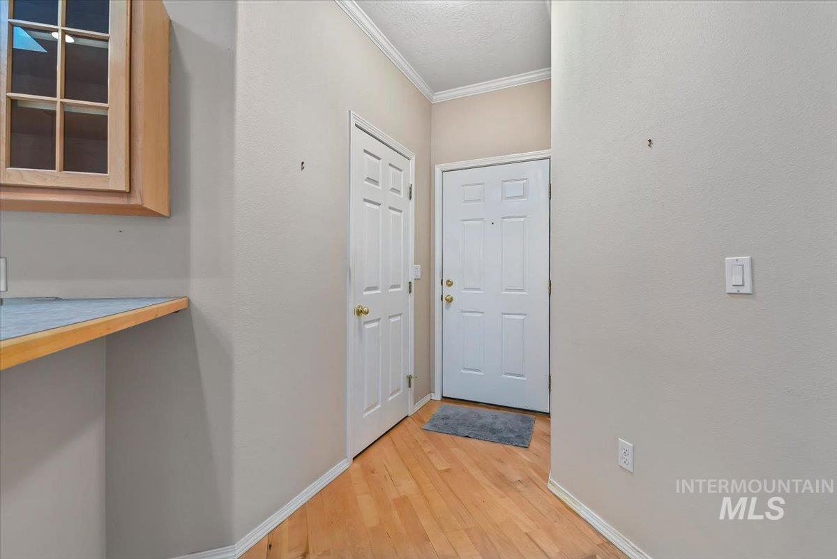 Doorway with crown molding and wood finished floors