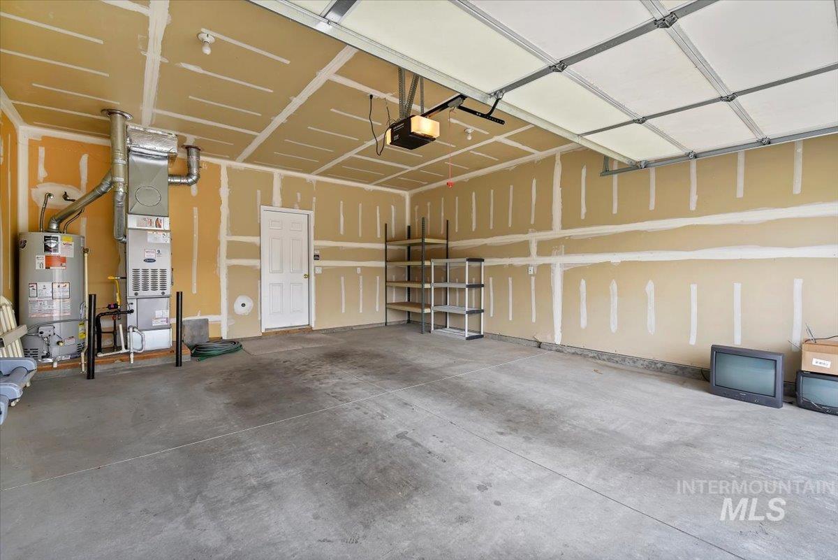 Garage with water heater, heating unit, and a garage door opener