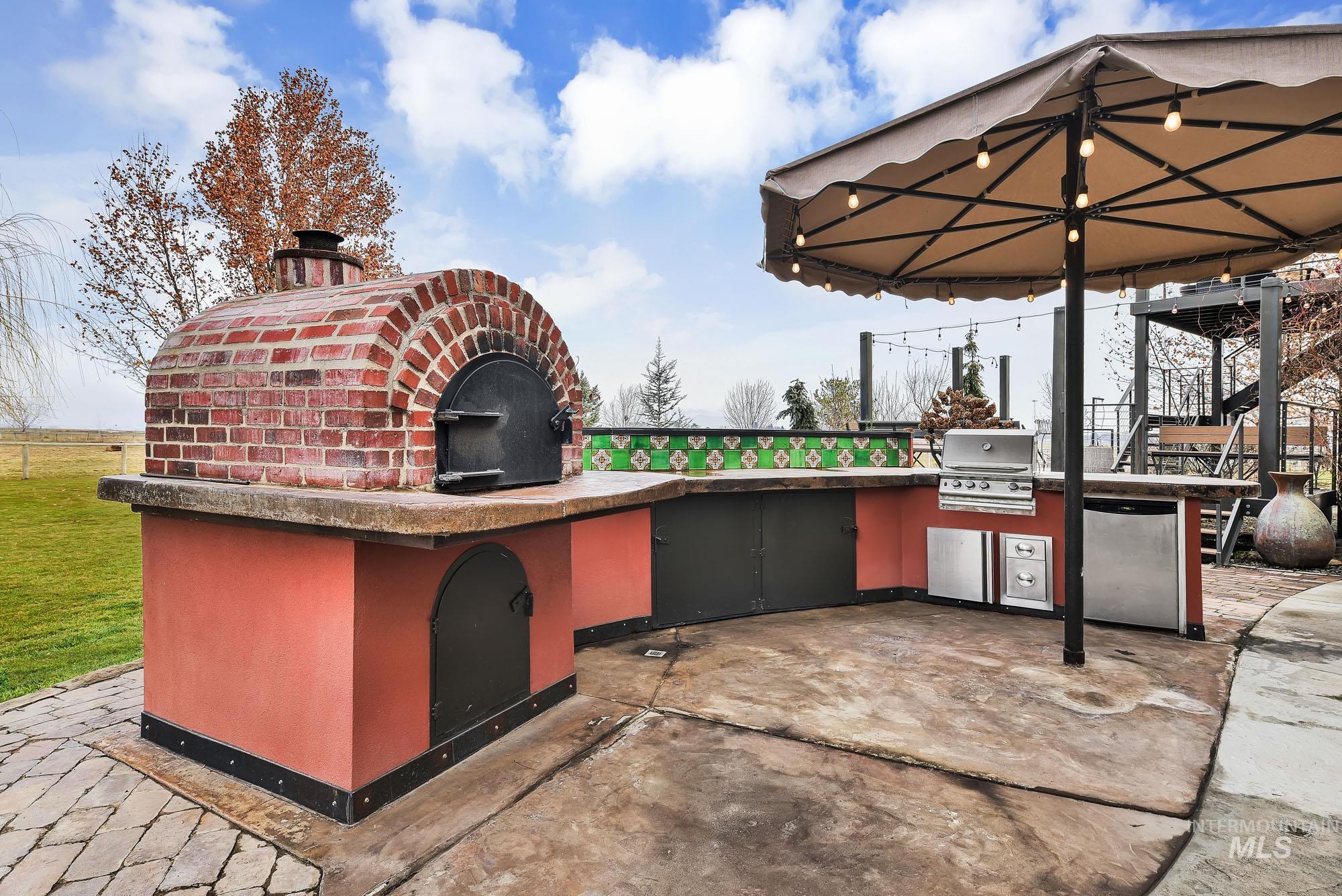 View of patio featuring area for grilling and full outdoor kitchen with pizza oven