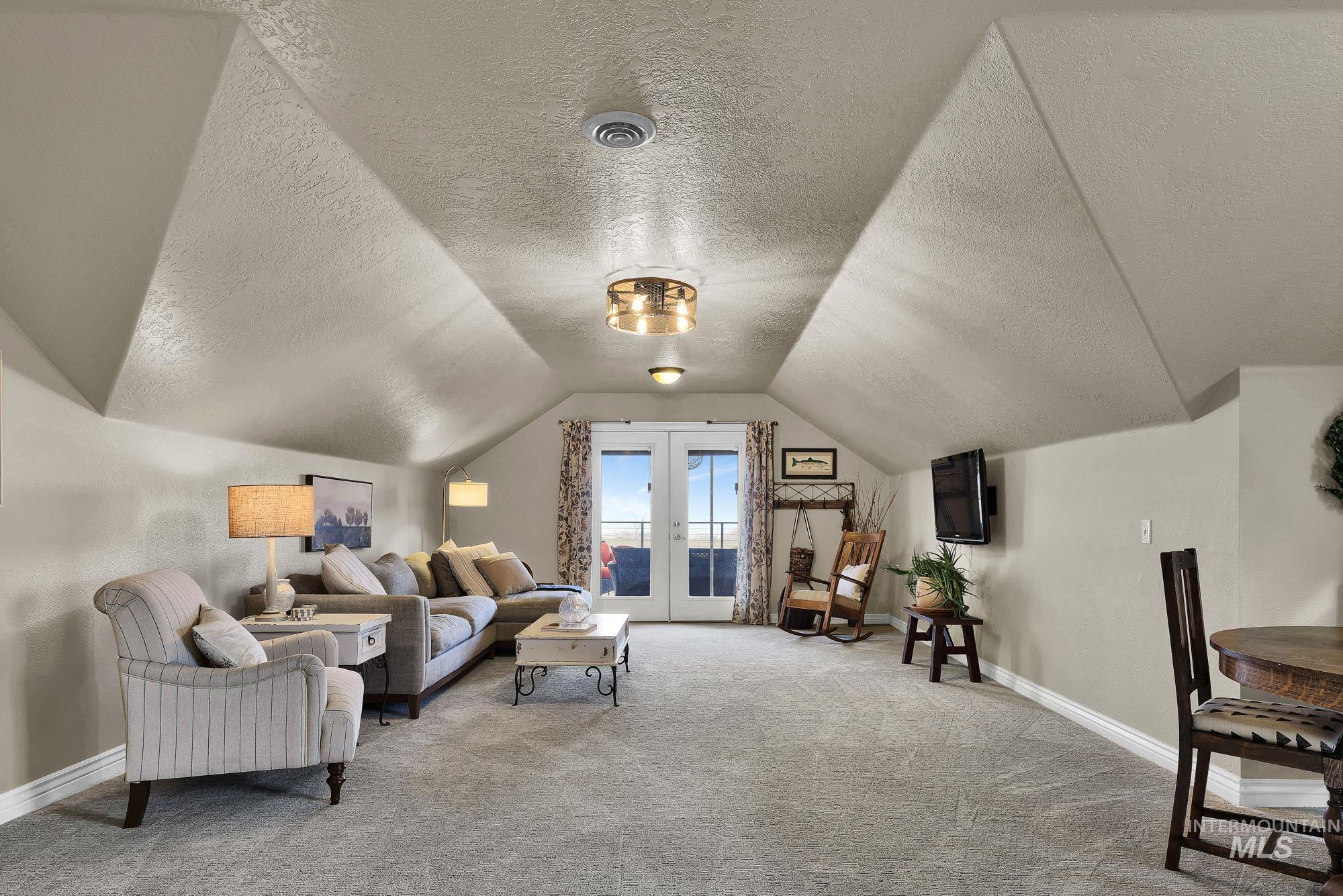 Rec room/ family room featuring an L shaped room with French doors to the covered deck, vaulted ceiling, and light carpet