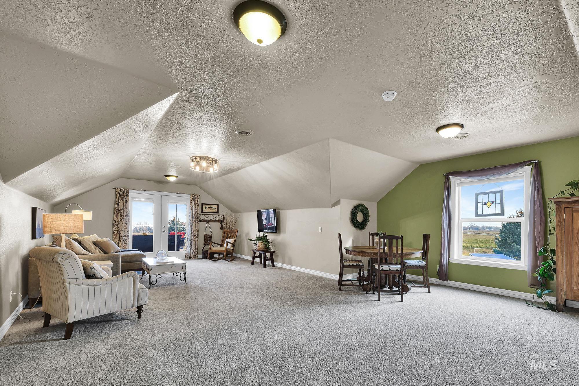 L-shaped rec room - family room with vaulted ceiling, healthy amount of natural light, and access to the covered deck with views of the mountains