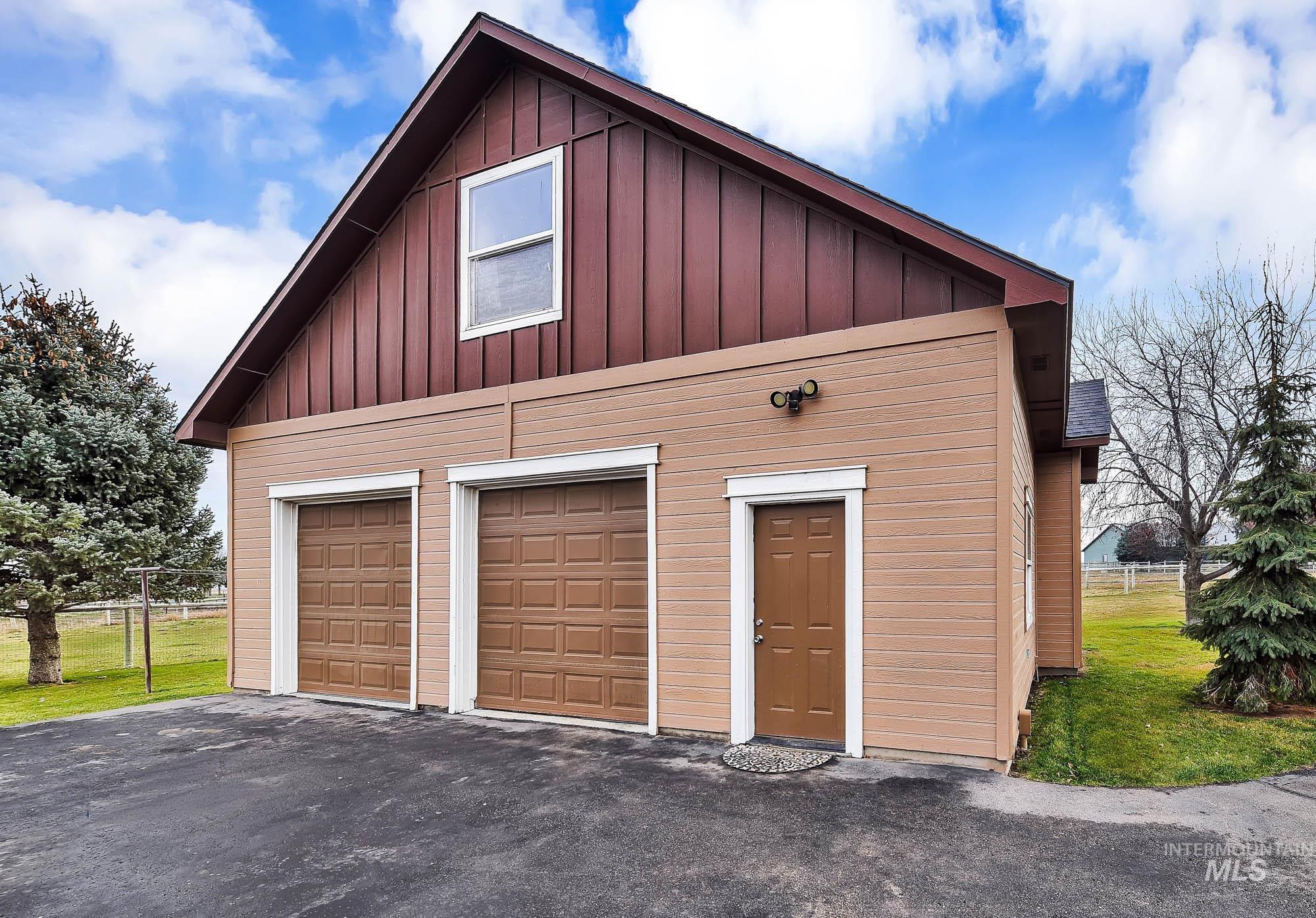 View of 2 car oversized garage/shop with garage doors and upper storage