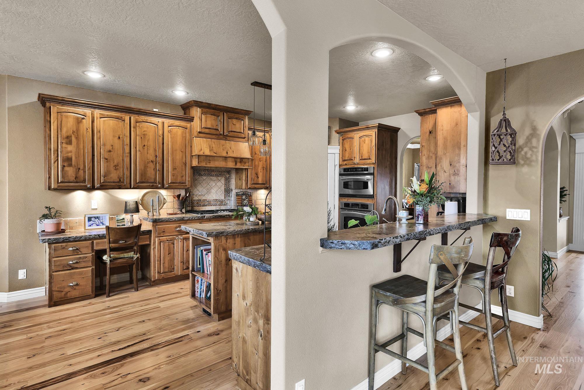Kitchen featuring light wood finished floors, a breakfast bar area, a peninsula, wood finish cabinetry, and recessed lighting
