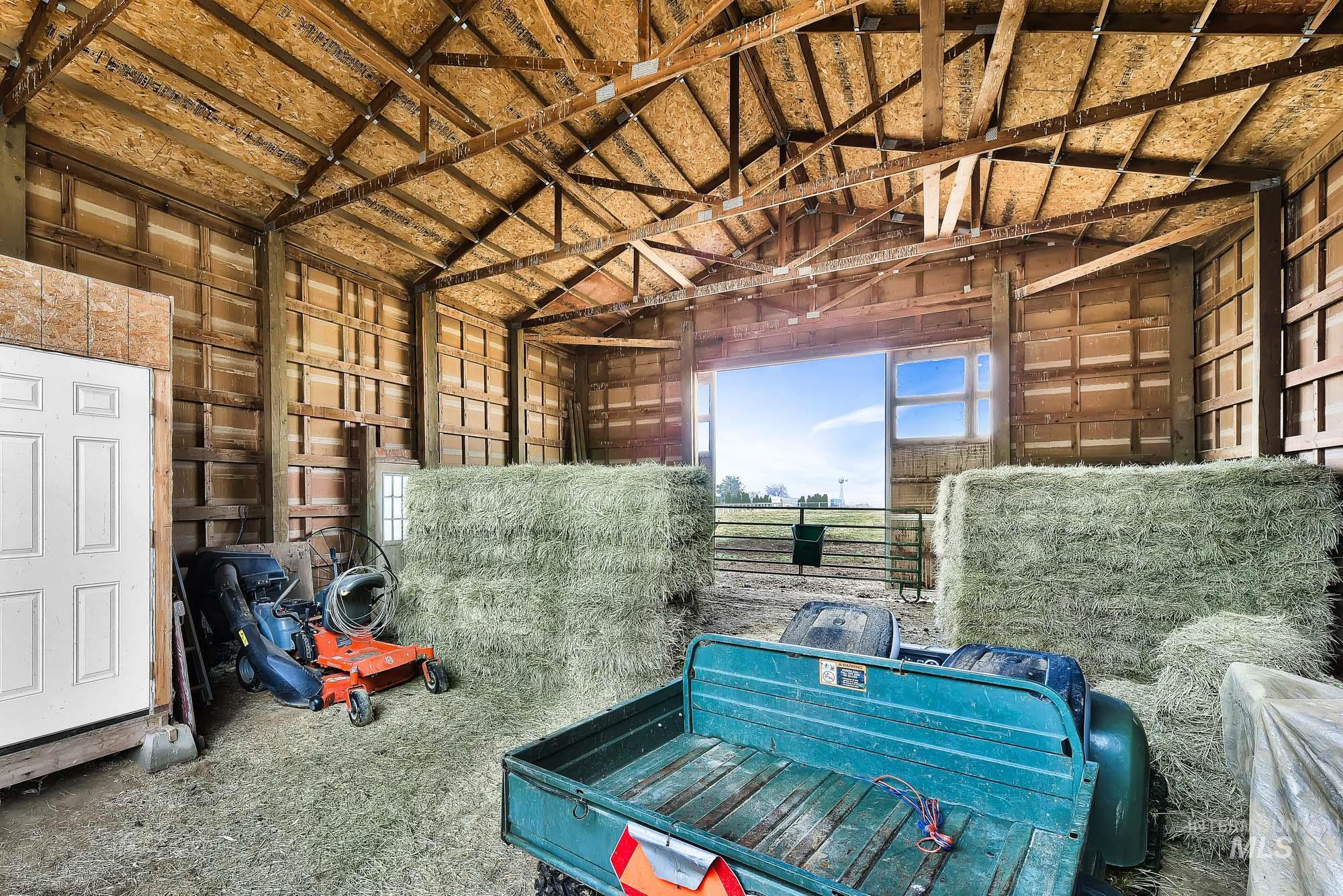 Covered barn area for hay and side tack room featuring lofted ceiling and doors on either end