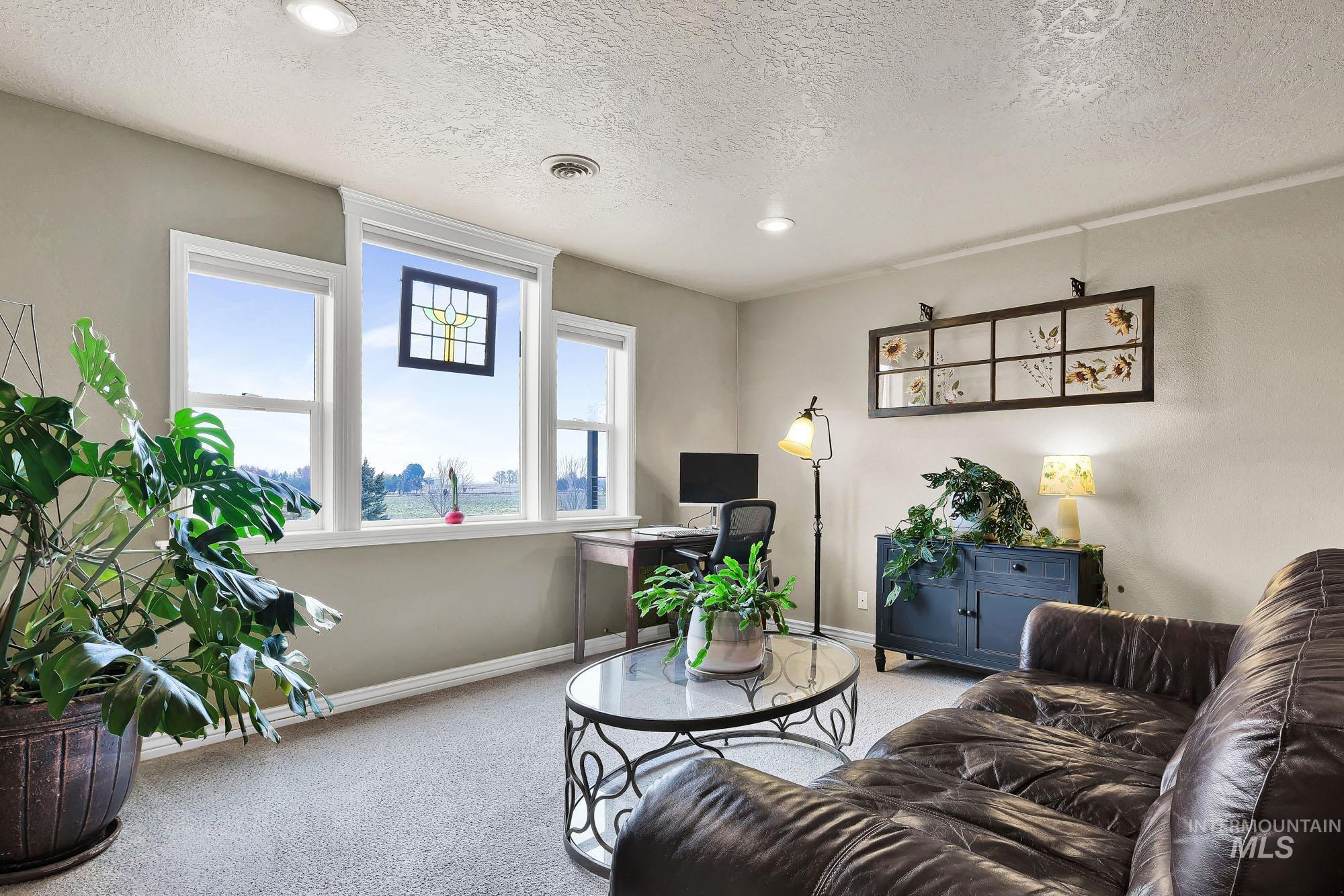 Living room with light carpet, recessed lighting, a textured ceiling, and a desk