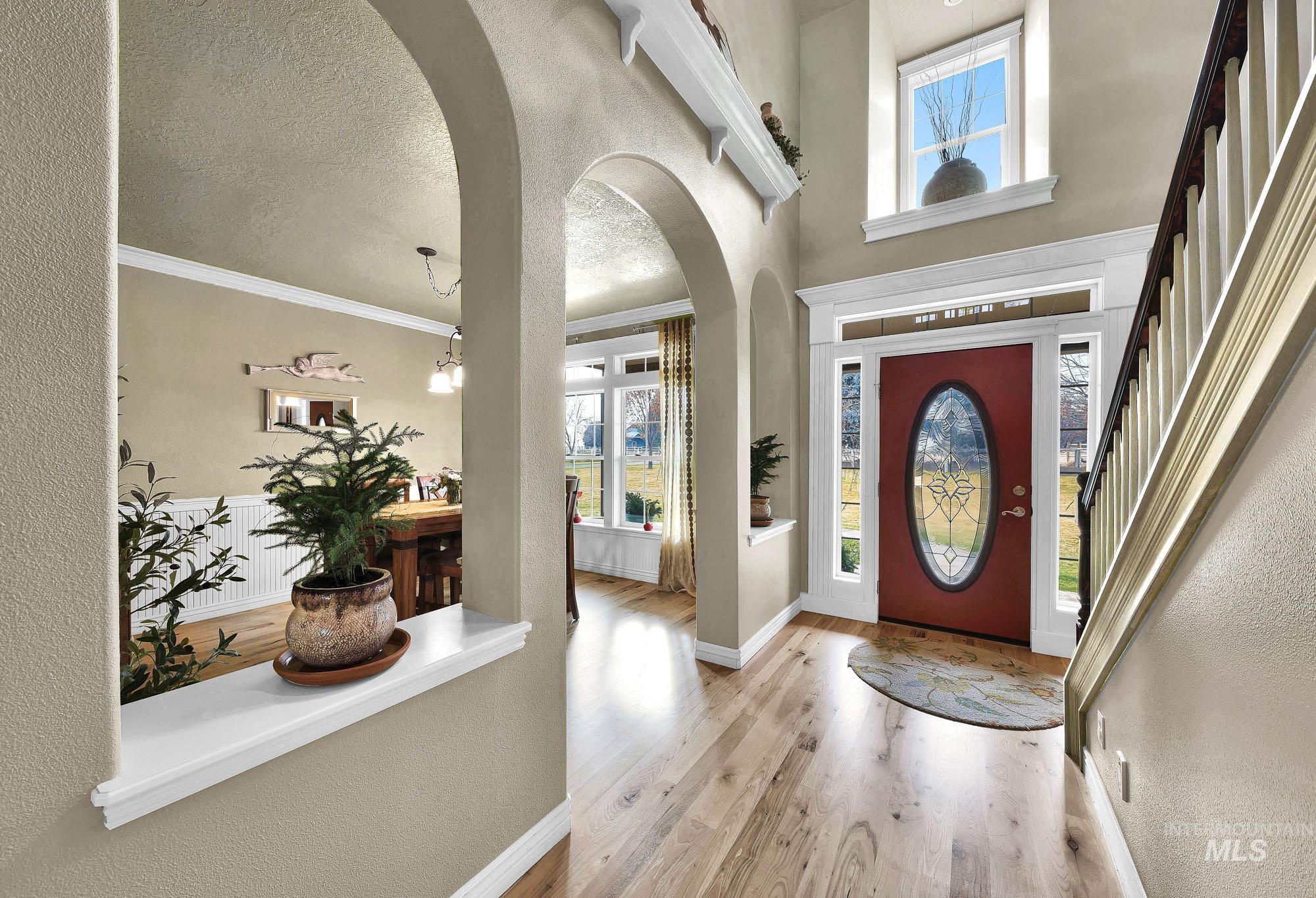 Entrance foyer featuring arched walkways, a textured wall, light wood-style flooring, and a textured ceiling