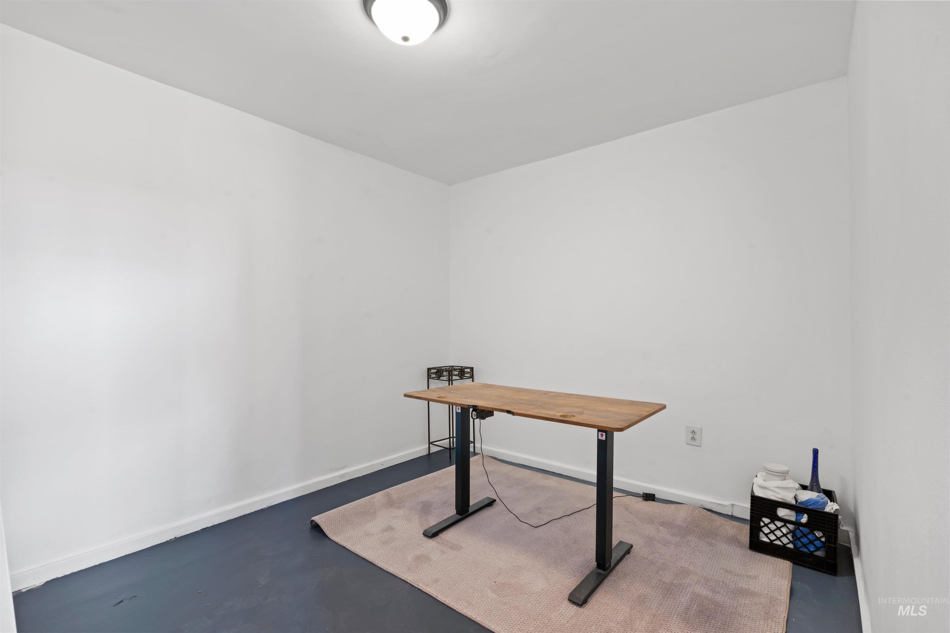 Unfurnished office with finished concrete flooring and baseboards