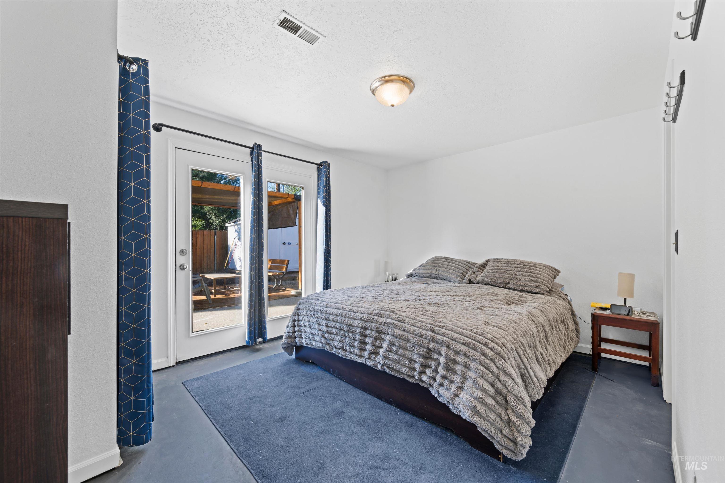 Bedroom featuring access to exterior, finished concrete flooring, and a textured ceiling