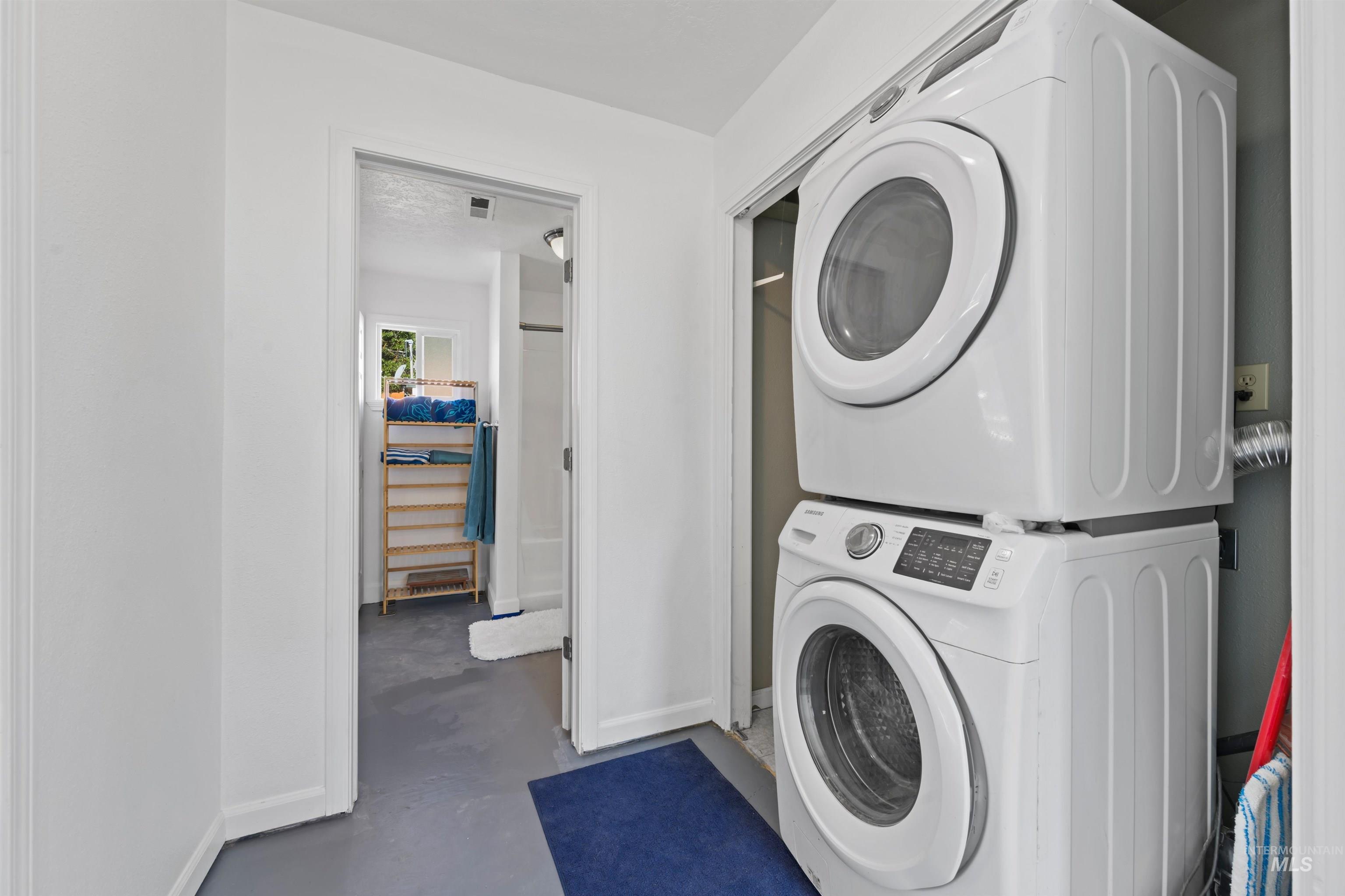 Laundry room with baseboards and stacked washer / drying machine