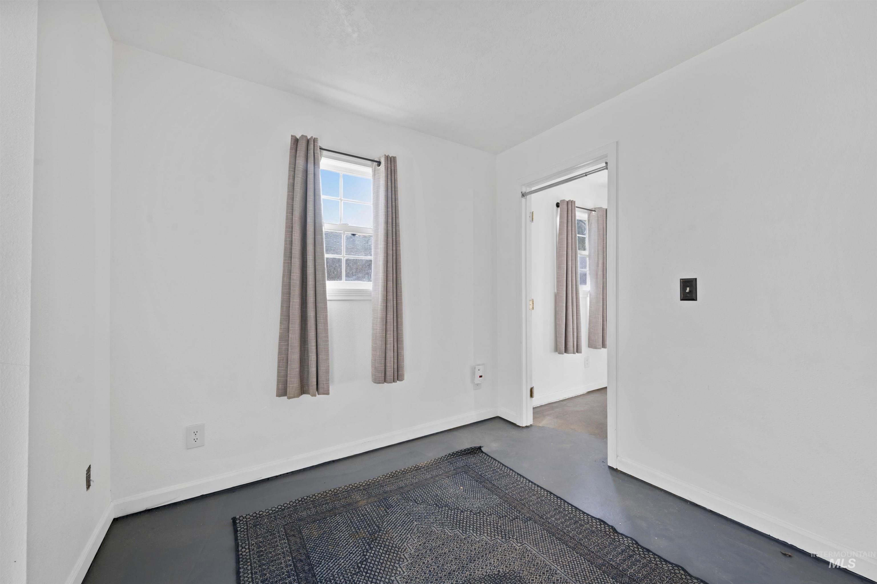 Spare room featuring concrete flooring and baseboards