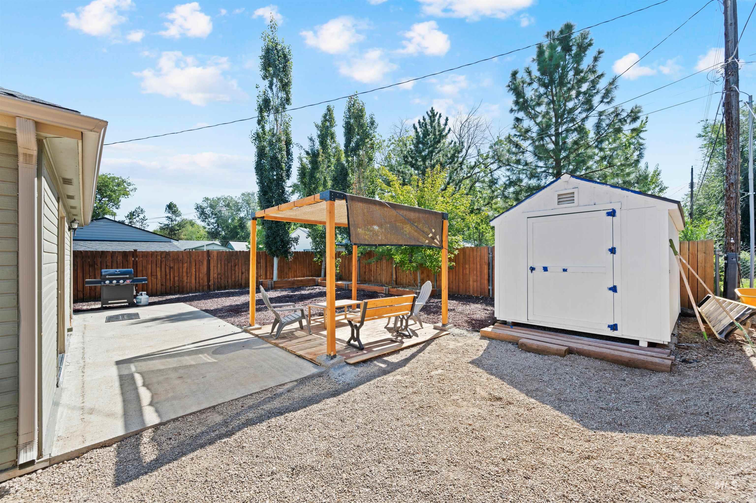 Fenced backyard featuring a patio area, a storage unit, and a grill