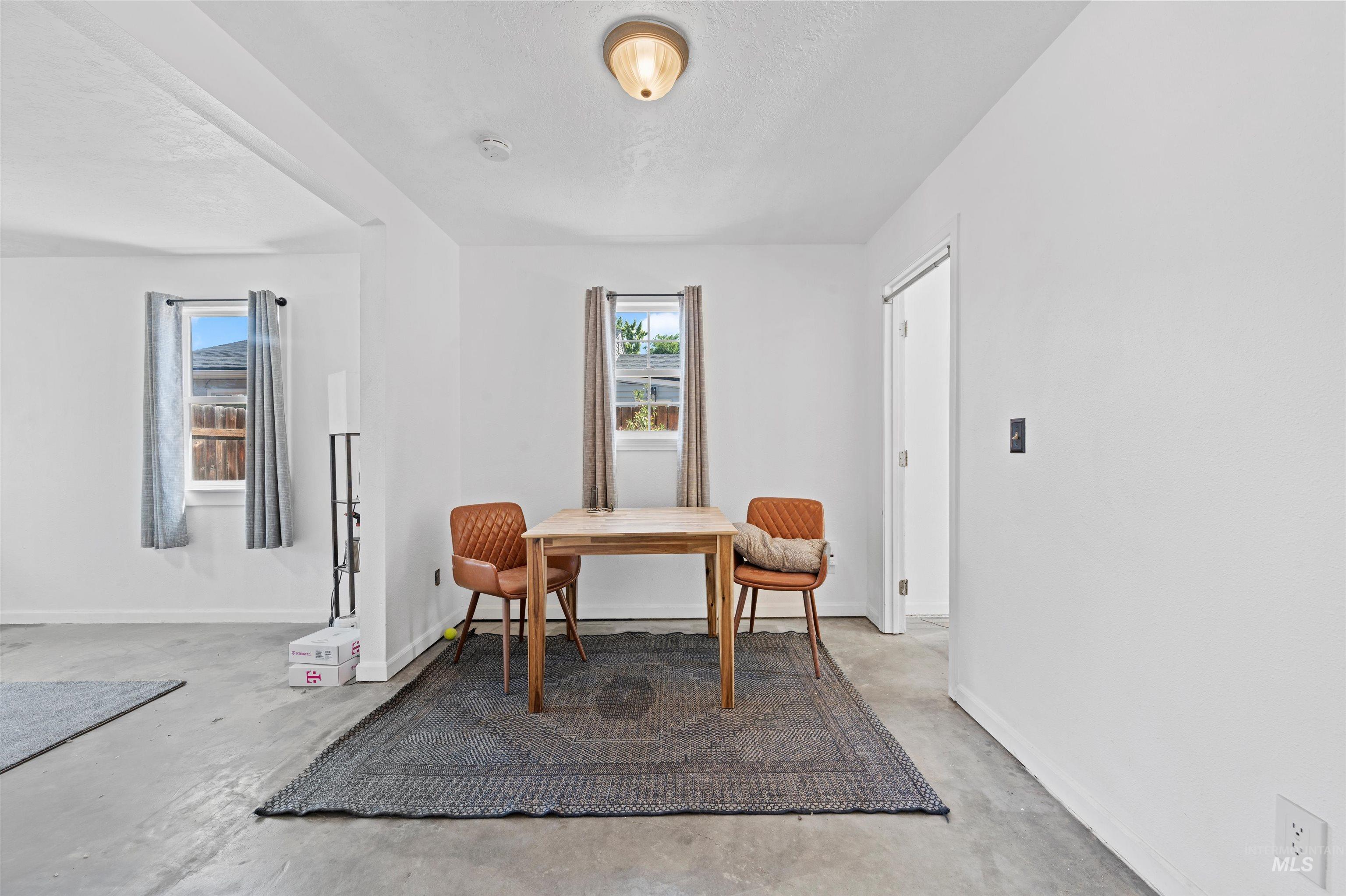 Living area with concrete flooring, a desk, and a textured ceiling