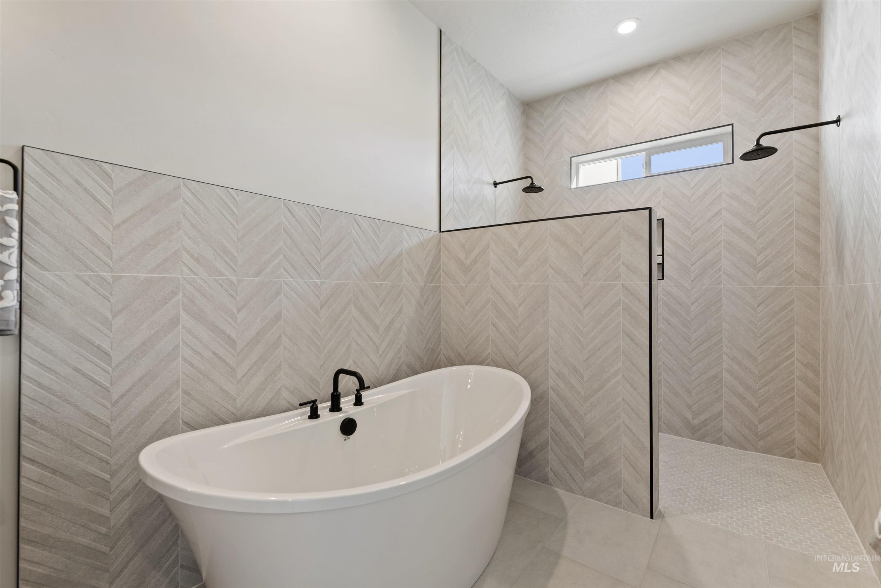 Bathroom featuring a walk in shower, a soaking tub, tile walls, and recessed lighting
