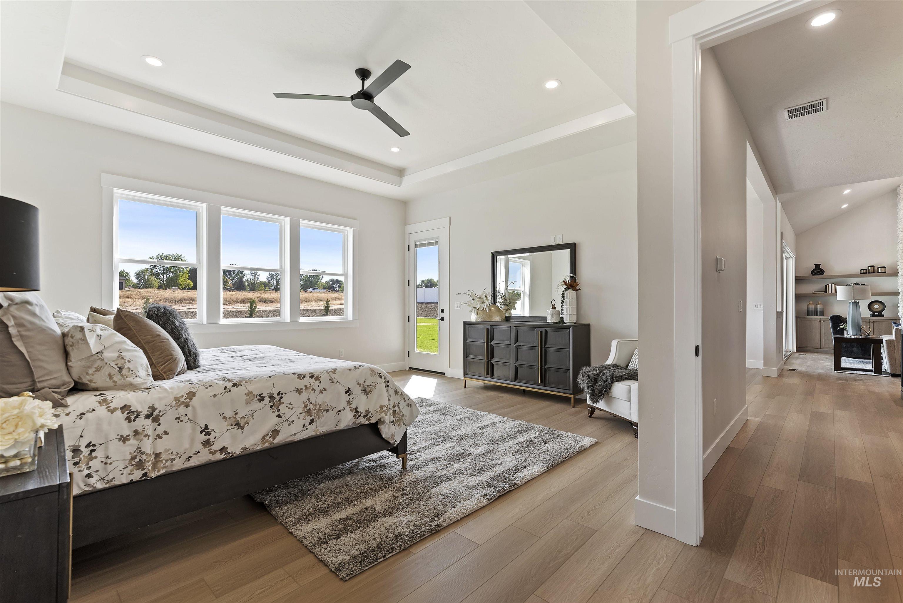 Bedroom with access to outside, light wood-type flooring, ceiling fan, recessed lighting, and a raised ceiling
