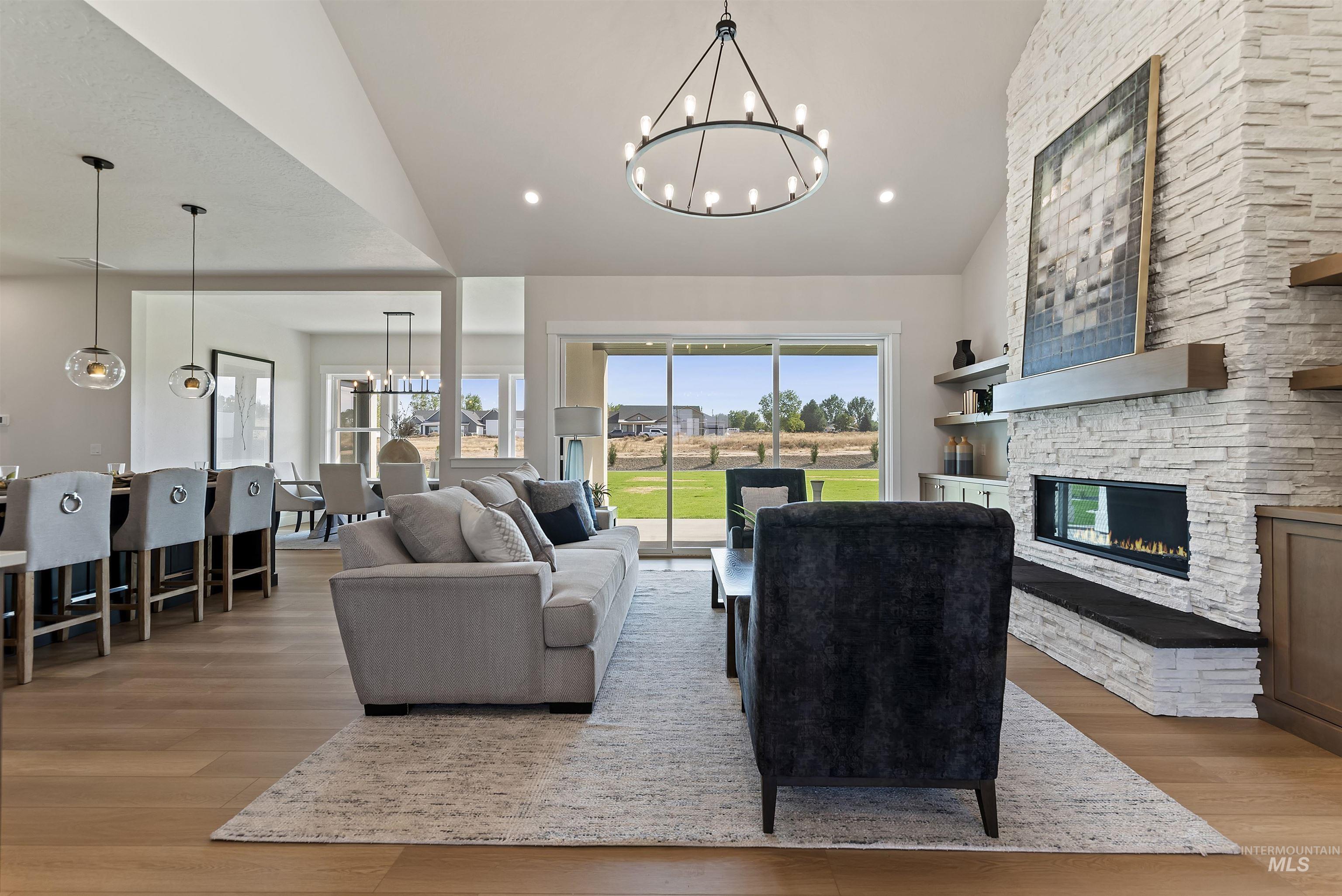 Living area featuring a chandelier, a fireplace, light wood finished floors, recessed lighting, and high vaulted ceiling