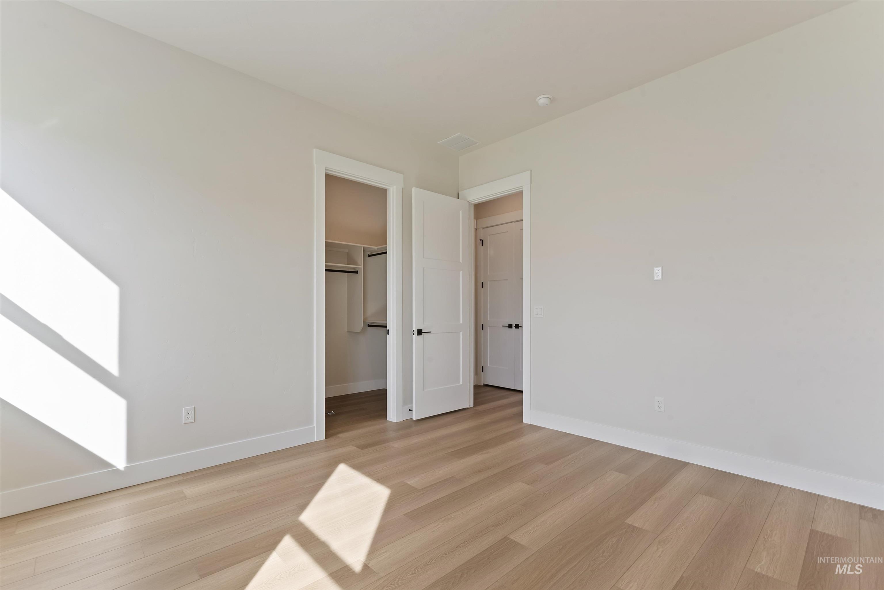 Unfurnished bedroom featuring a walk in closet and light wood-style floors