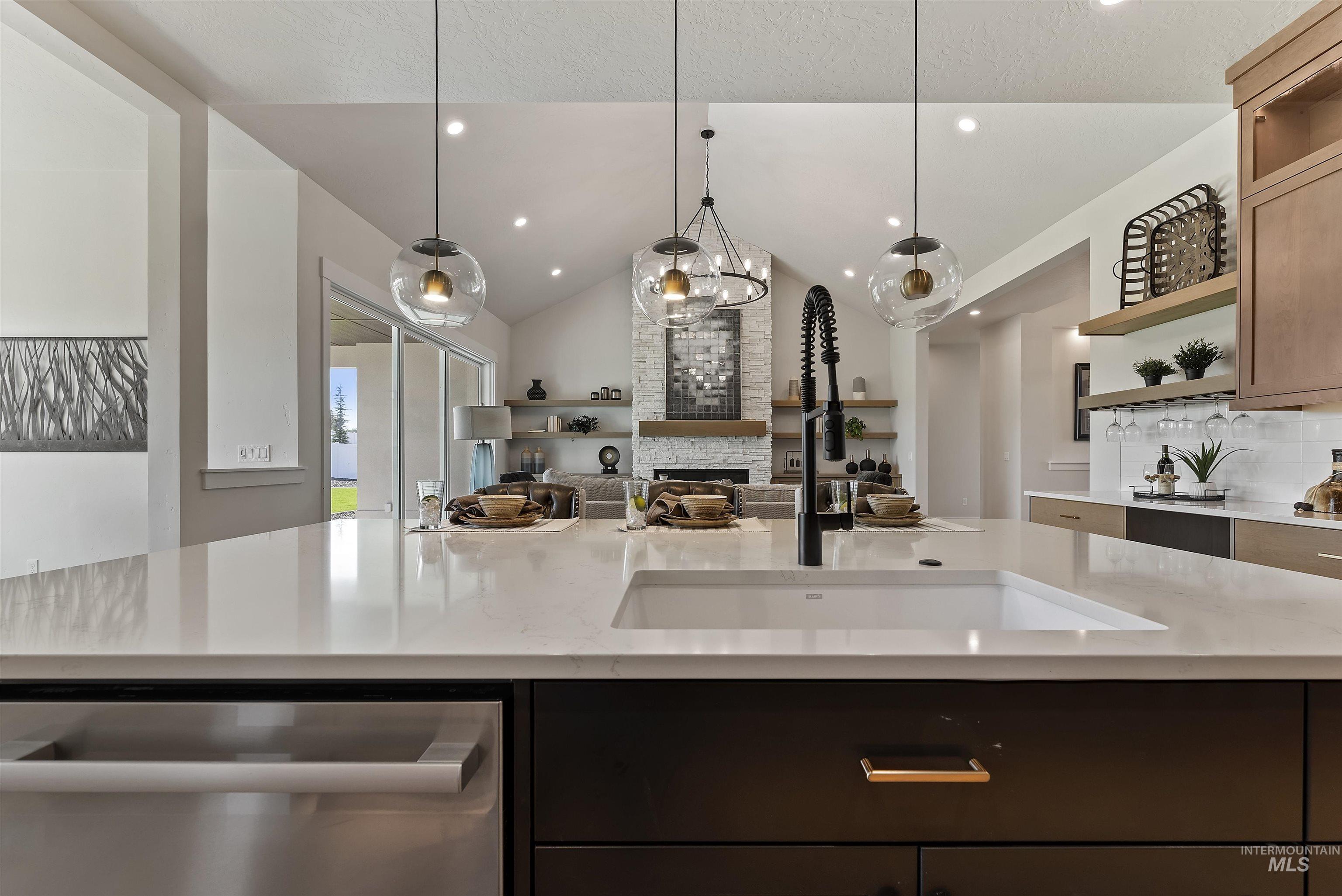 Kitchen featuring open floor plan, pendant lighting, dishwasher, decorative backsplash, and lofted ceiling