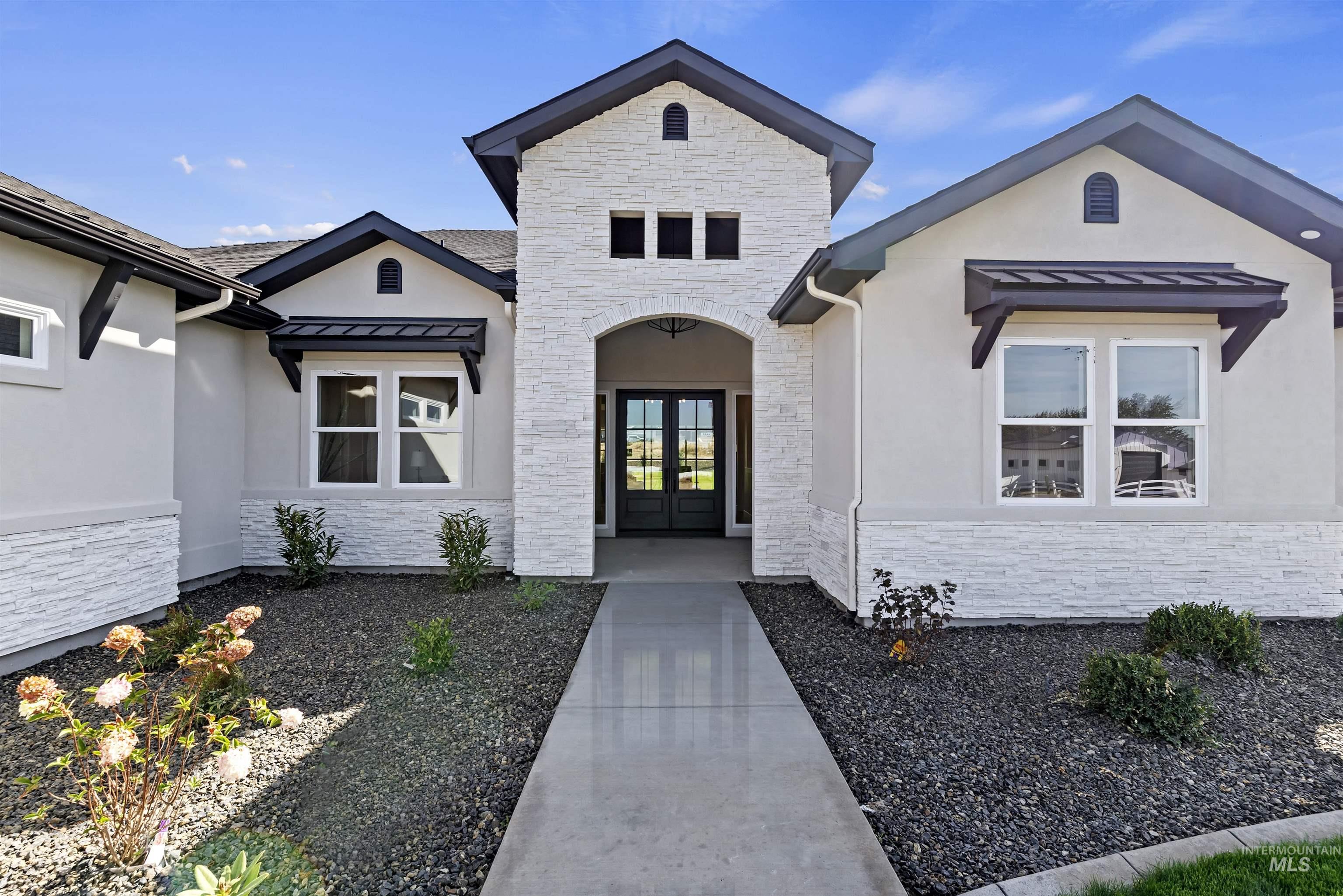 View of exterior entry with a standing seam roof, stone siding, a metal roof, and stucco siding