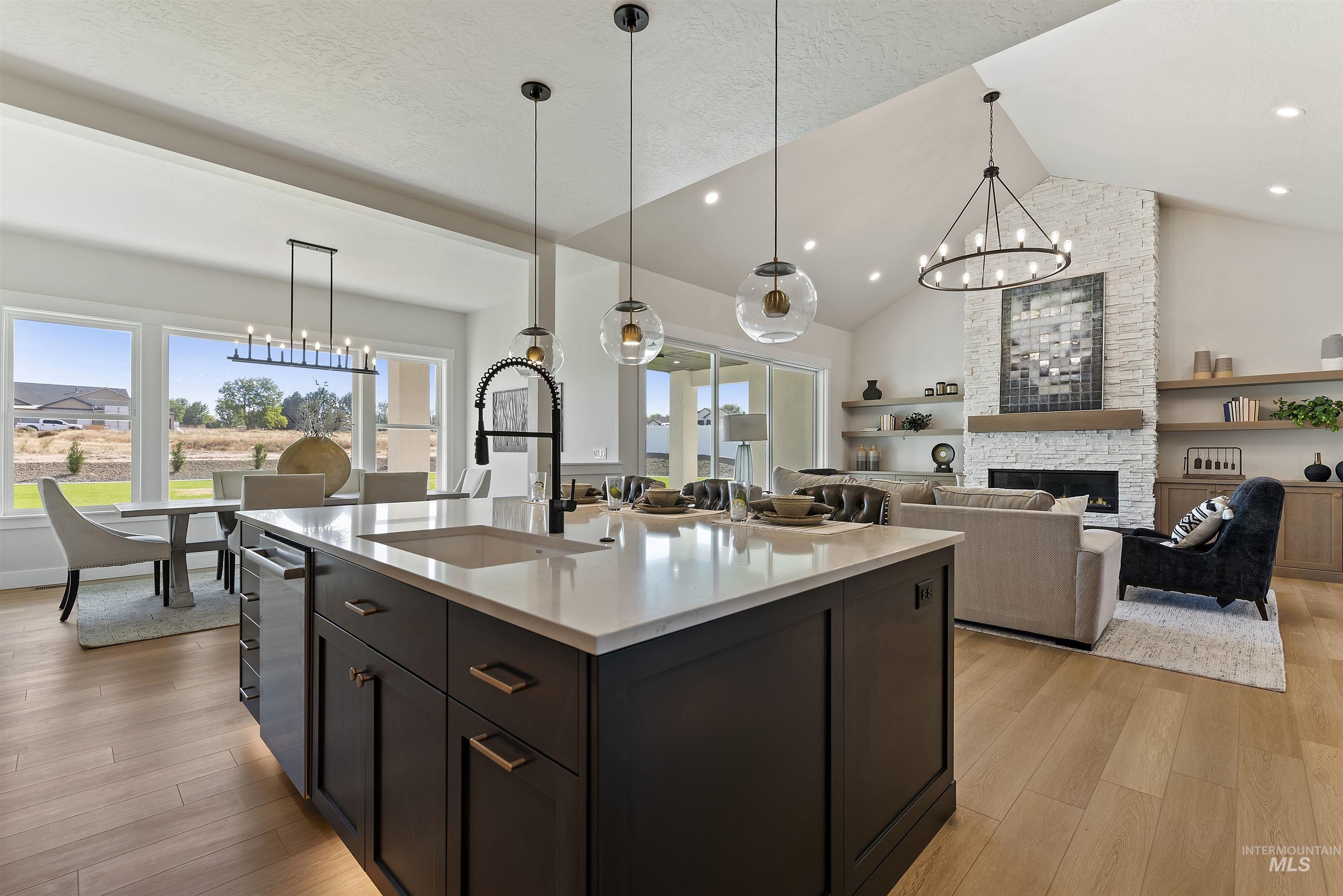 Kitchen featuring a chandelier, pendant lighting, a fireplace, open floor plan, and high vaulted ceiling