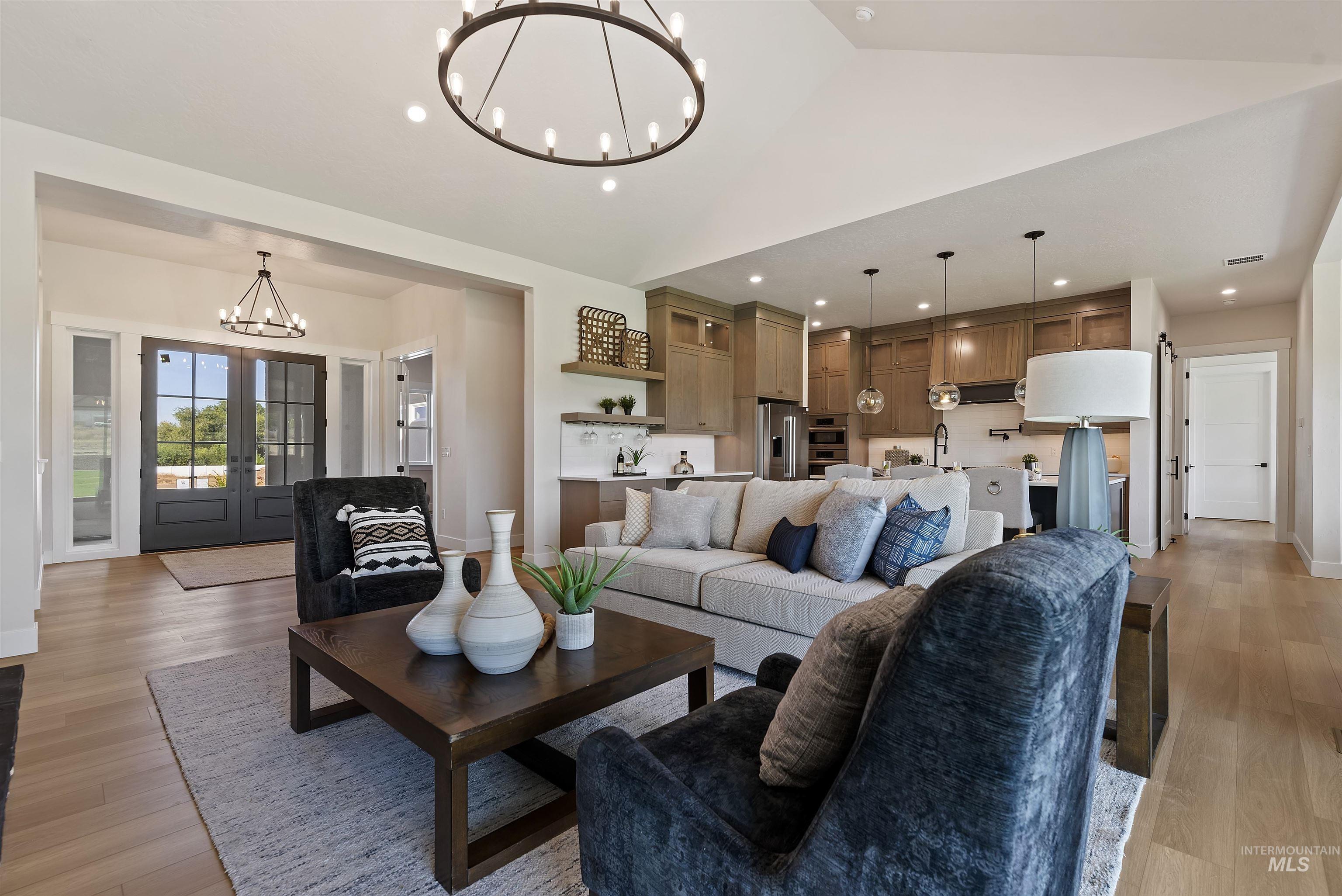 Living area with a chandelier, french doors, light wood-style flooring, recessed lighting, and lofted ceiling