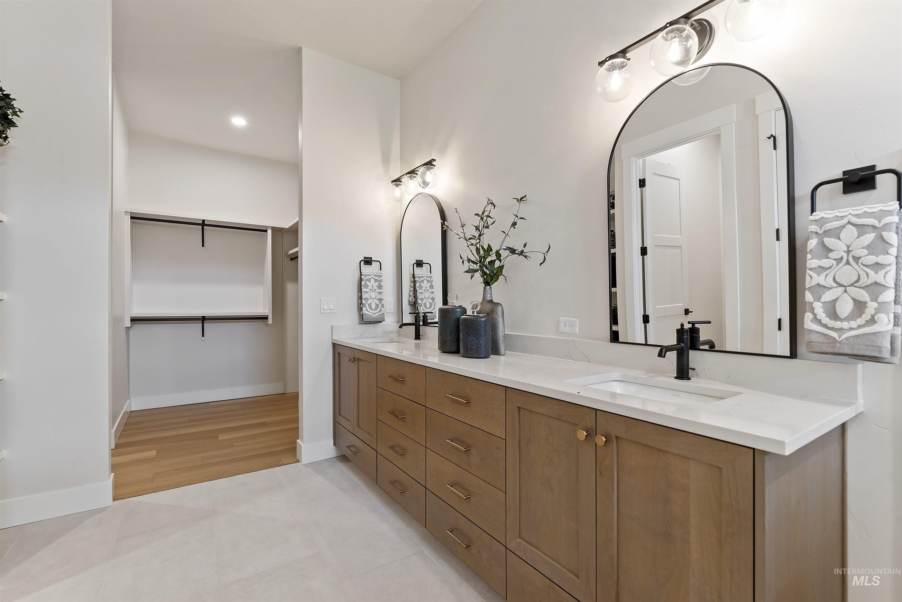 Bathroom with double vanity, light tile patterned floors, recessed lighting, and a spacious closet