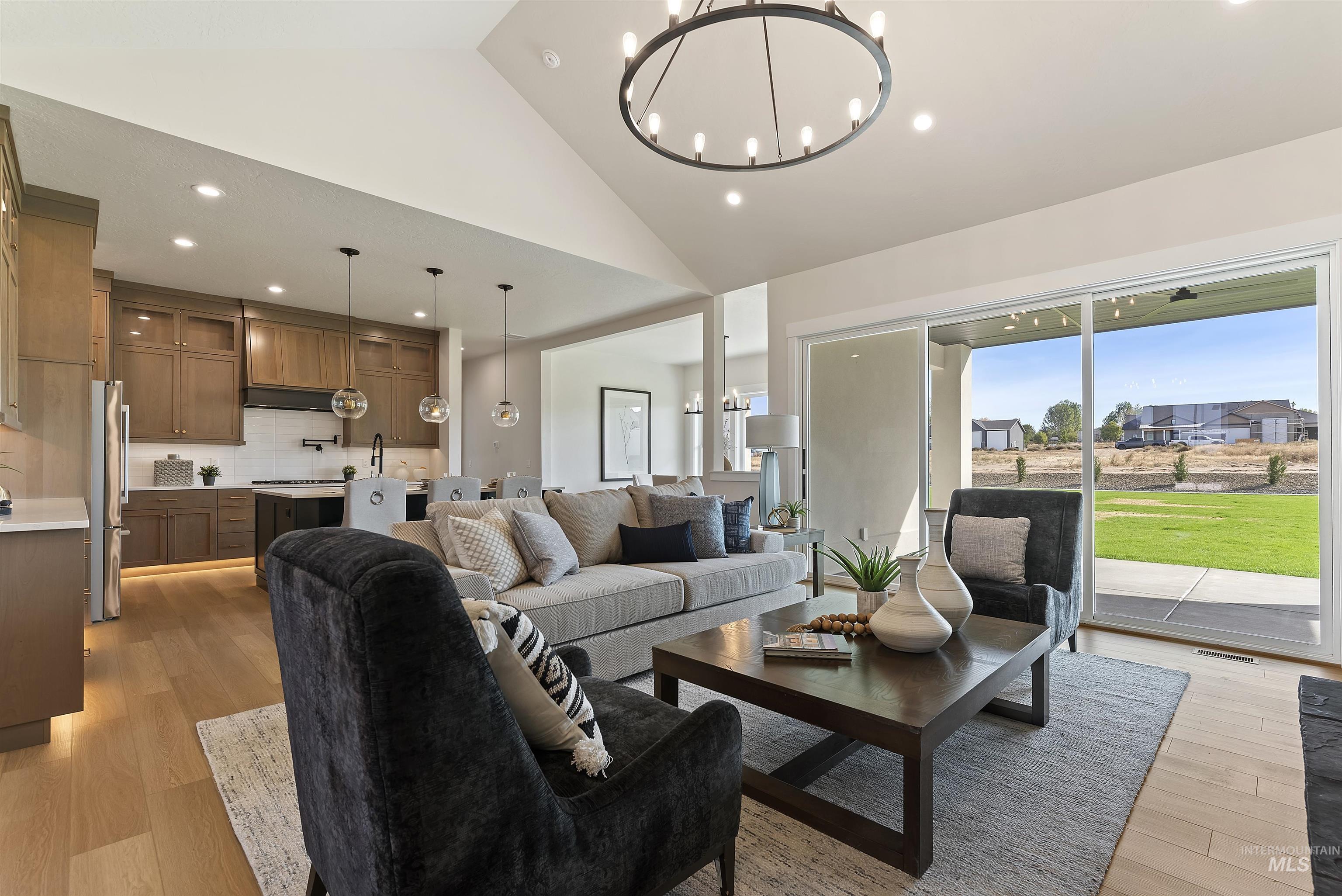Living room with light wood-style flooring, recessed lighting, a chandelier, and high vaulted ceiling