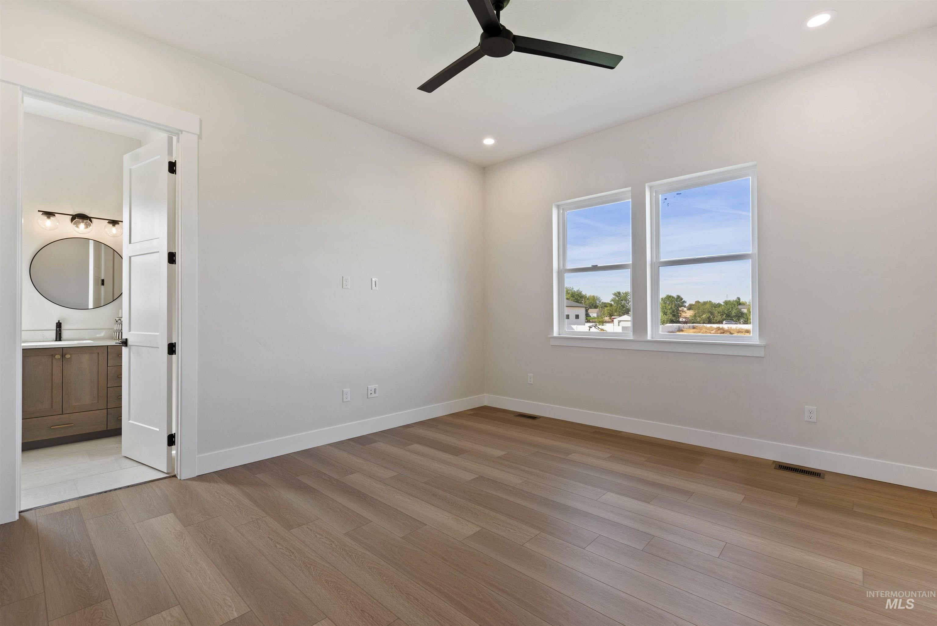 Unfurnished bedroom with light wood finished floors, a ceiling fan, recessed lighting, and connected bathroom