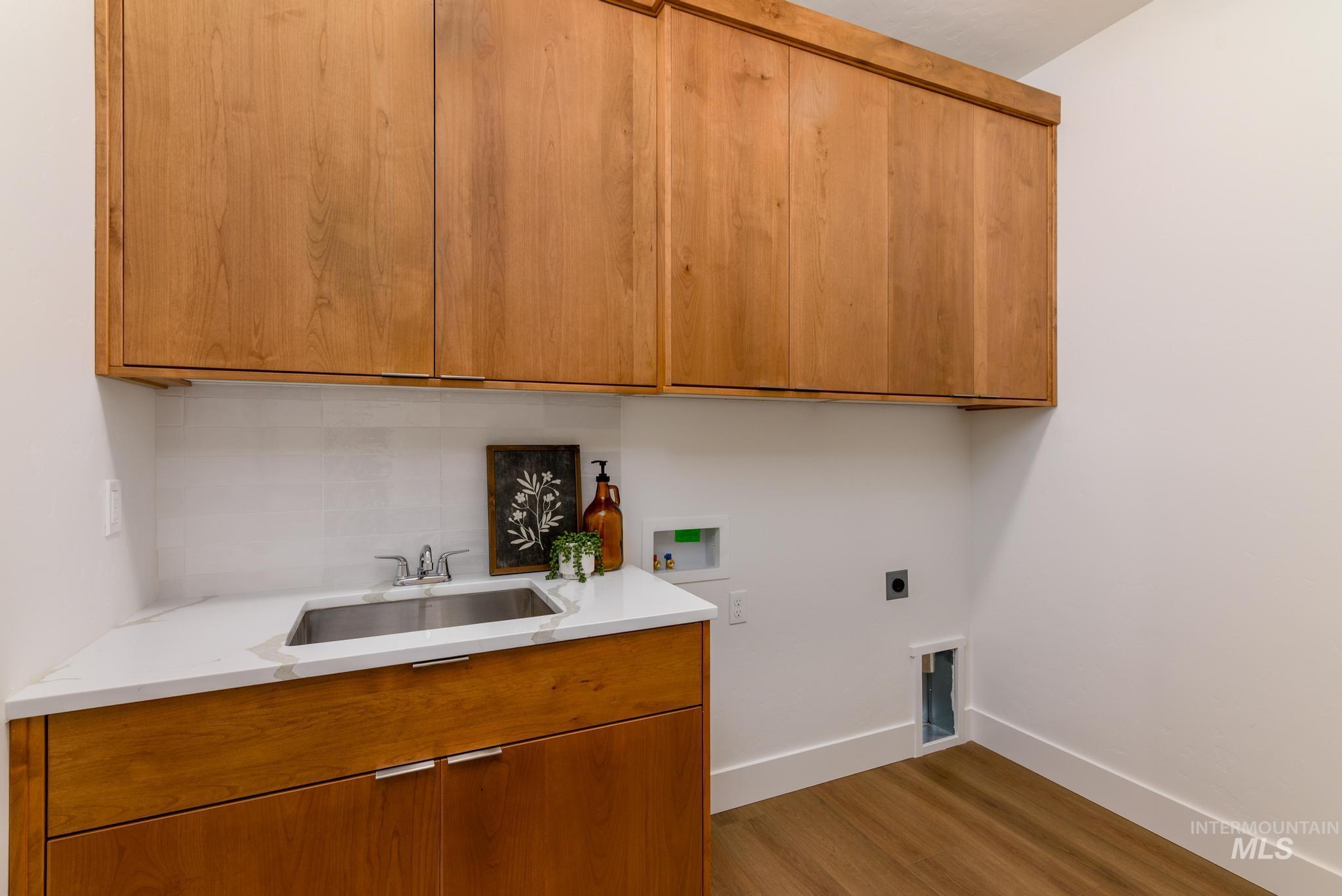 Laundry area with washer hookup, cabinet space, electric dryer hookup, and light wood-style floors