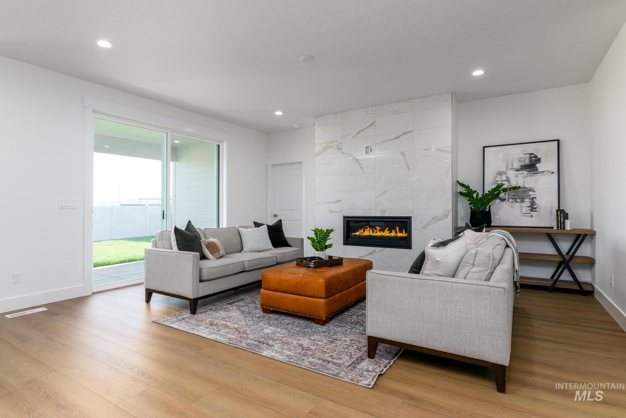 Living area with a fireplace, light wood-type flooring, and recessed lighting