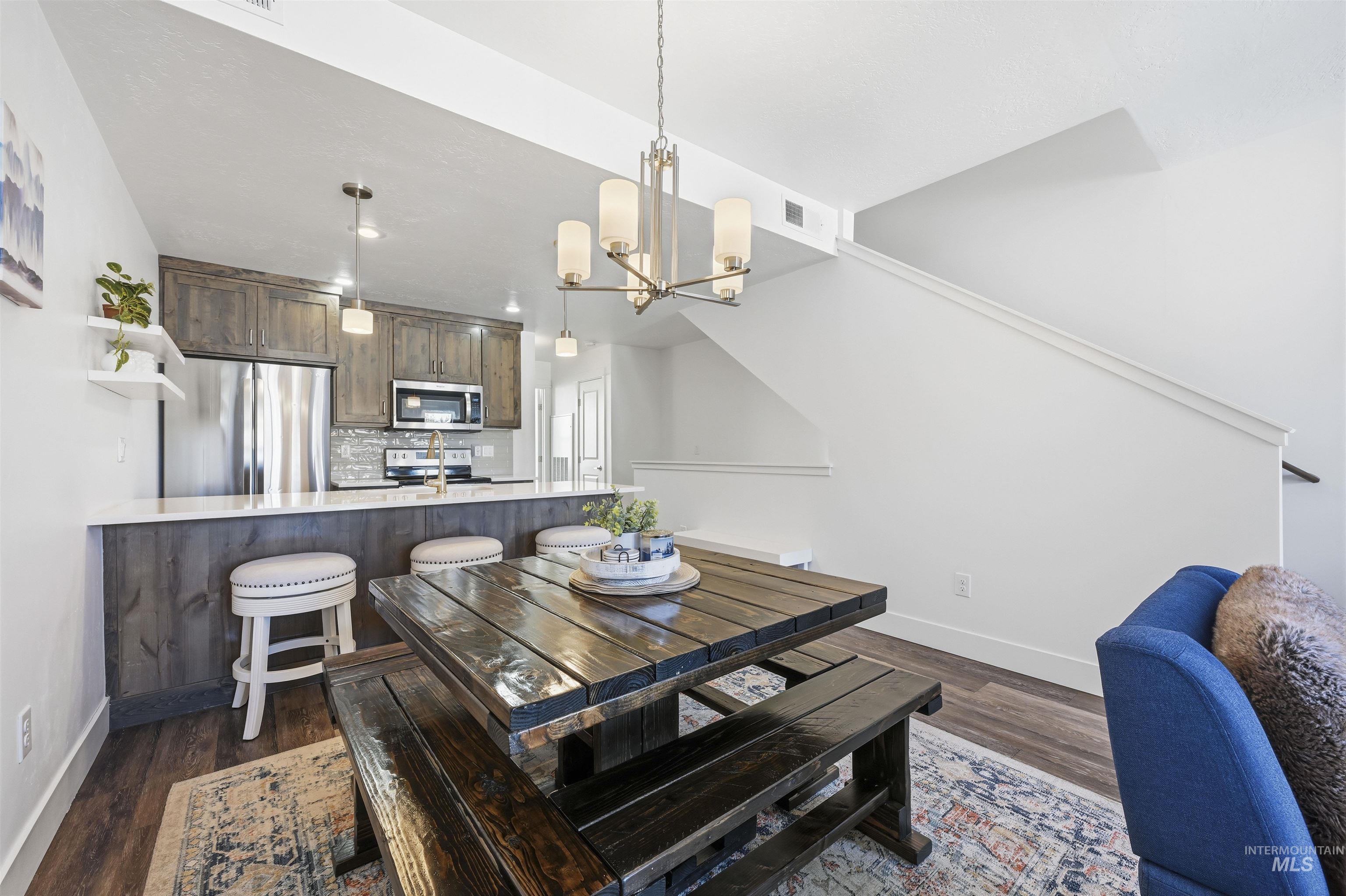 Dining room with hanging lights and dark wood-style floors