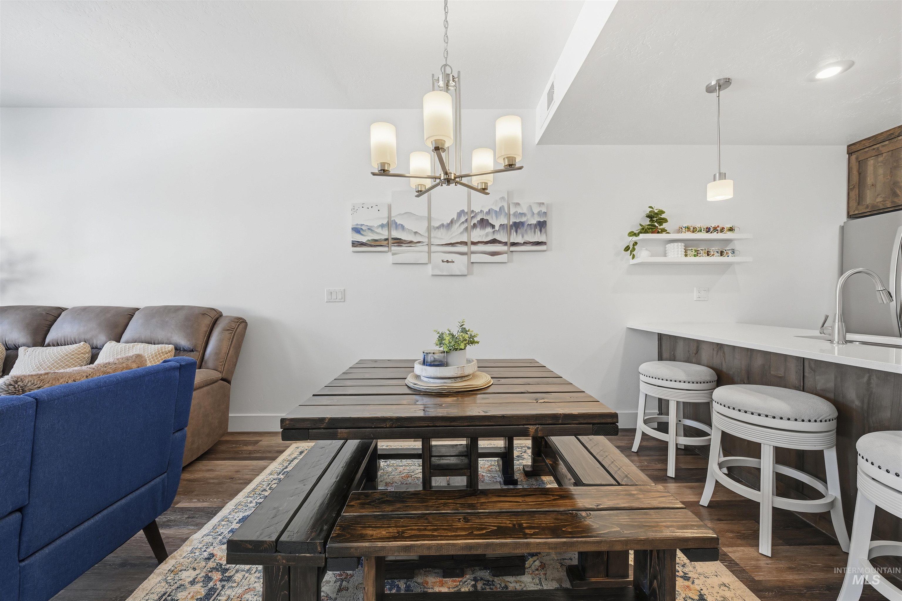 Dining room featuring dark wood-style flooring and hanging lights