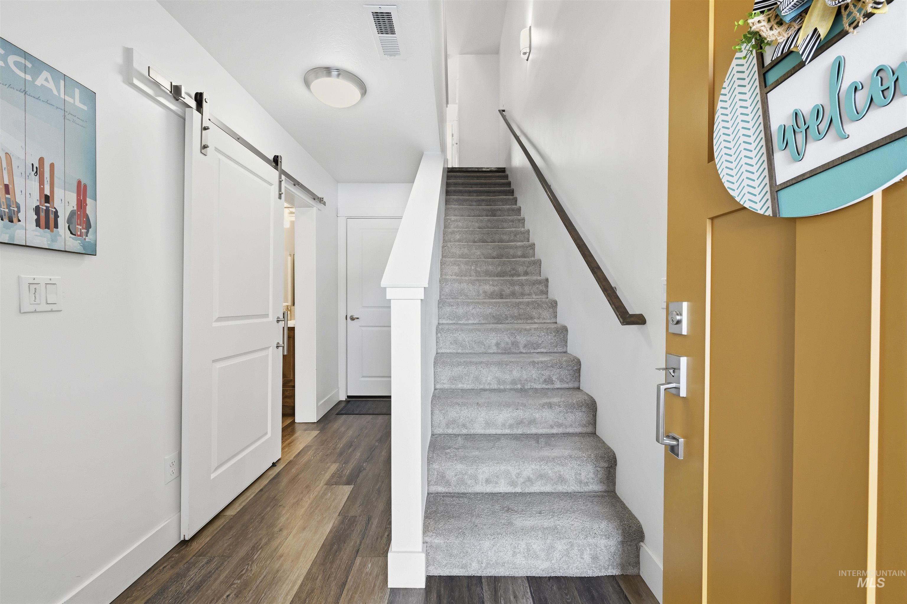Stairway featuring a barn door and wood finished floors