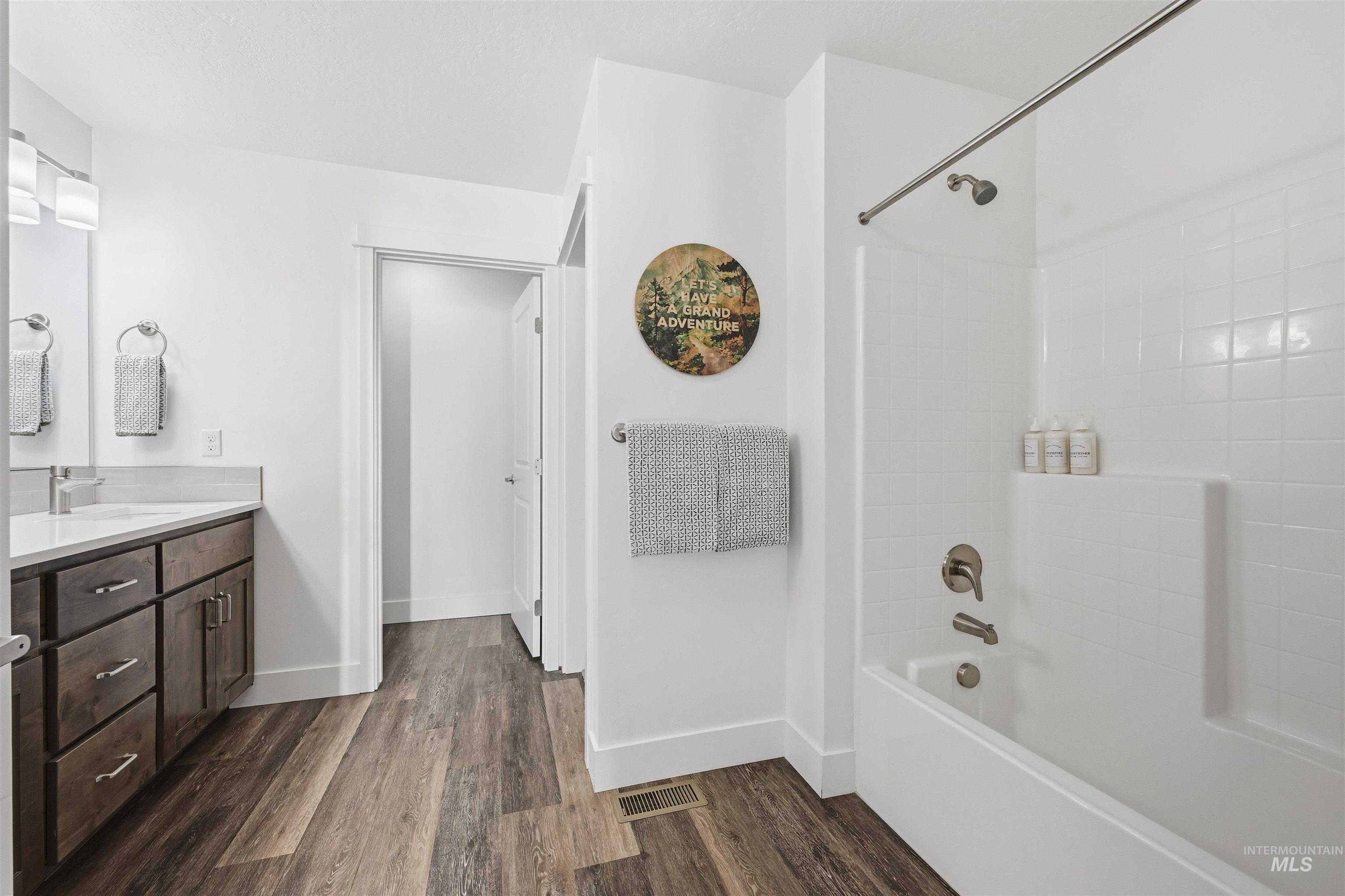 Full bath featuring vanity, bathtub / shower combination, and dark wood finished floors