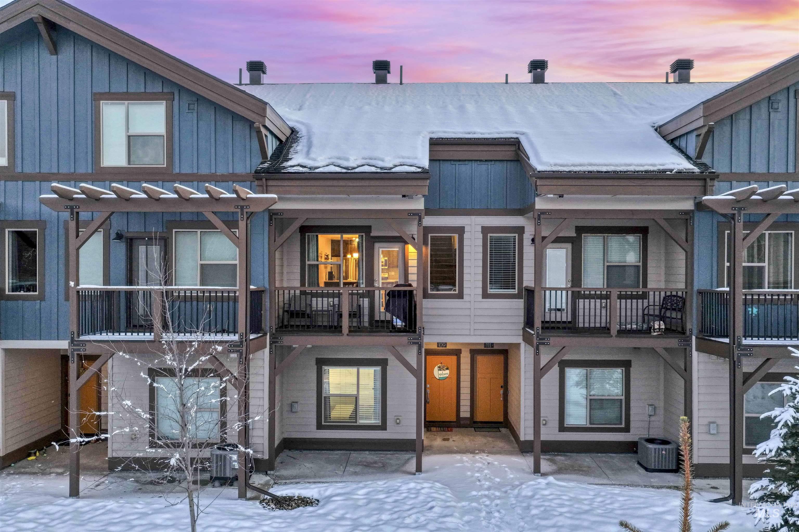 Snow covered back of property featuring board and batten siding, a metal roof, and a patio area