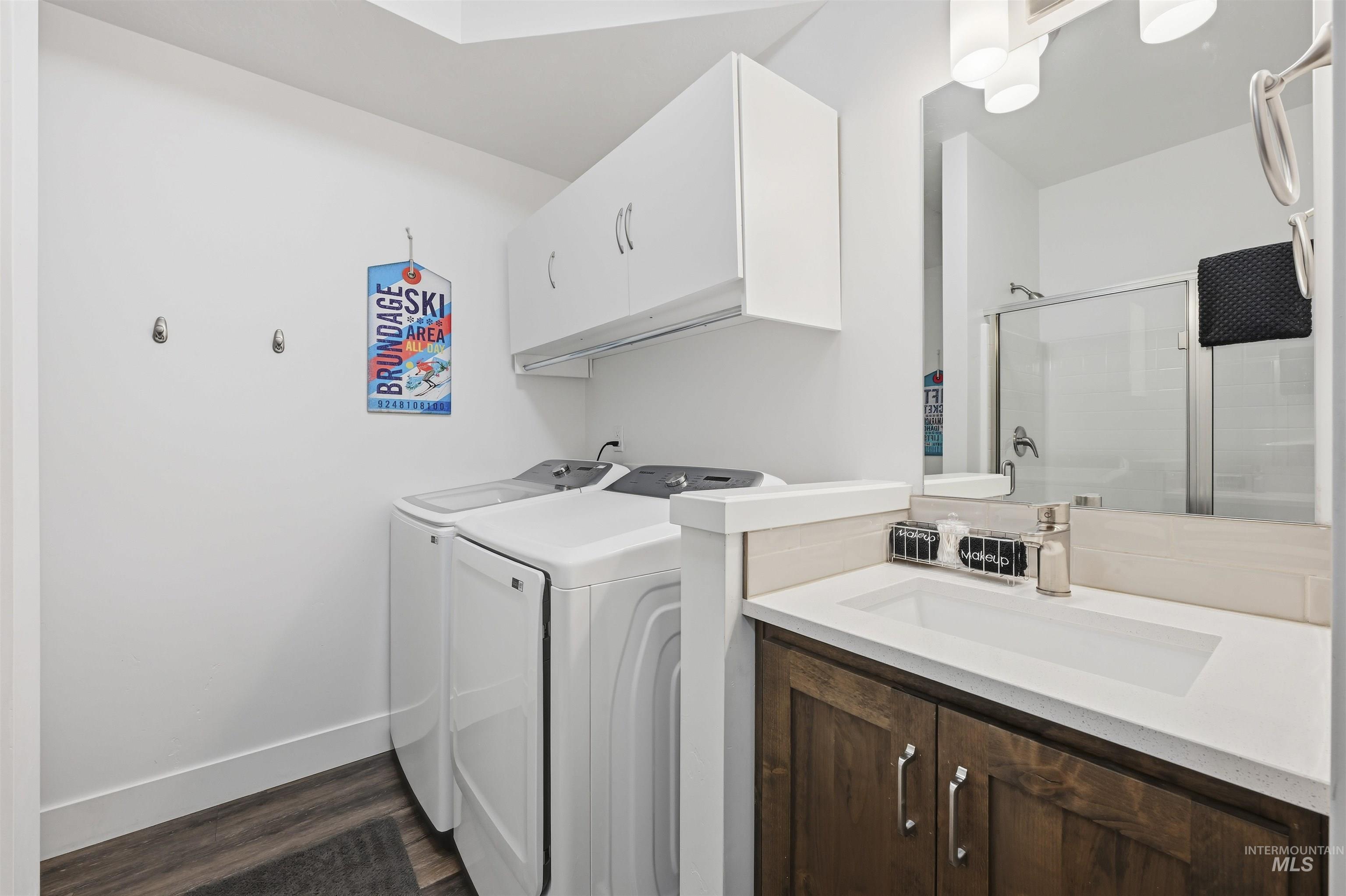 Laundry area with dark wood finished floors and washing machine and clothes dryer