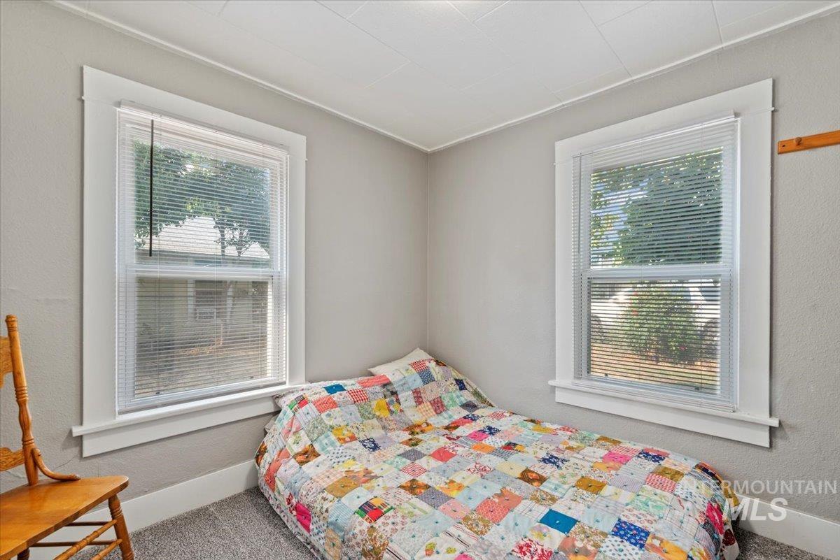 Carpeted bedroom with multiple windows and a textured wall
