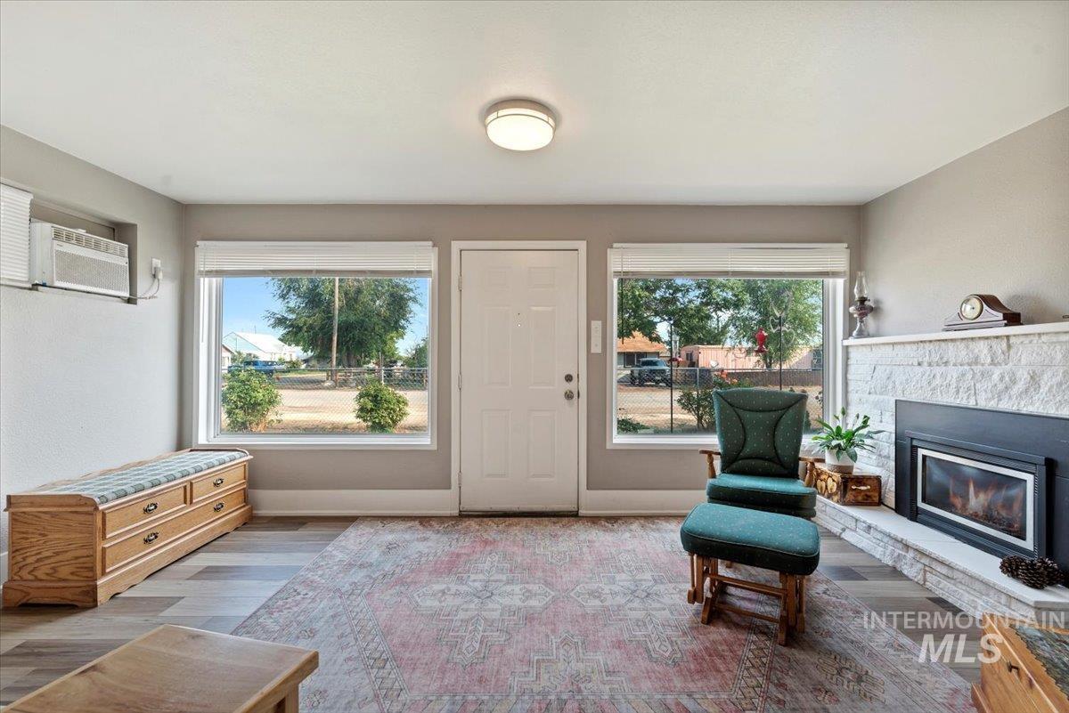 Living area with wood finished floors, a fireplace, and a wall mounted air conditioner