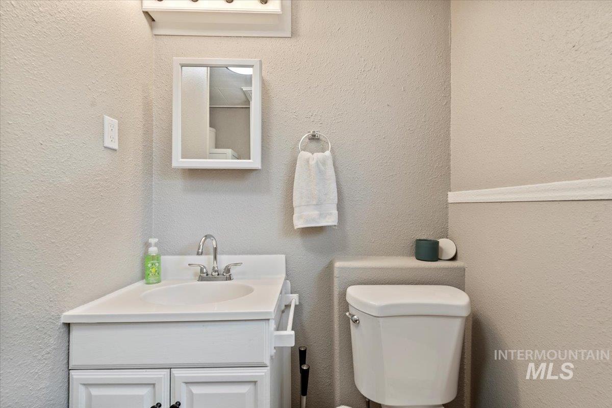 Half bath with a textured wall and vanity
