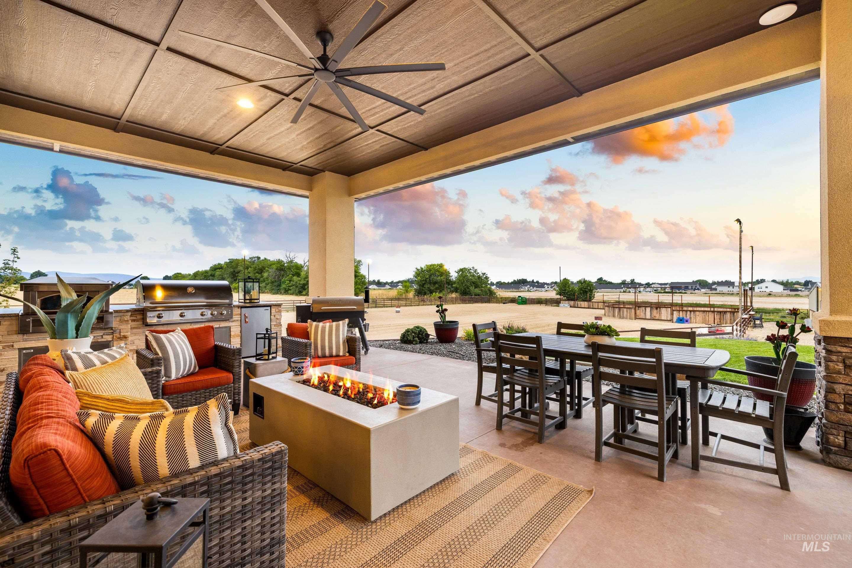 Patio terrace at dusk with exterior kitchen, an outdoor fire pit, outdoor dining area, a patio area, and a ceiling fan