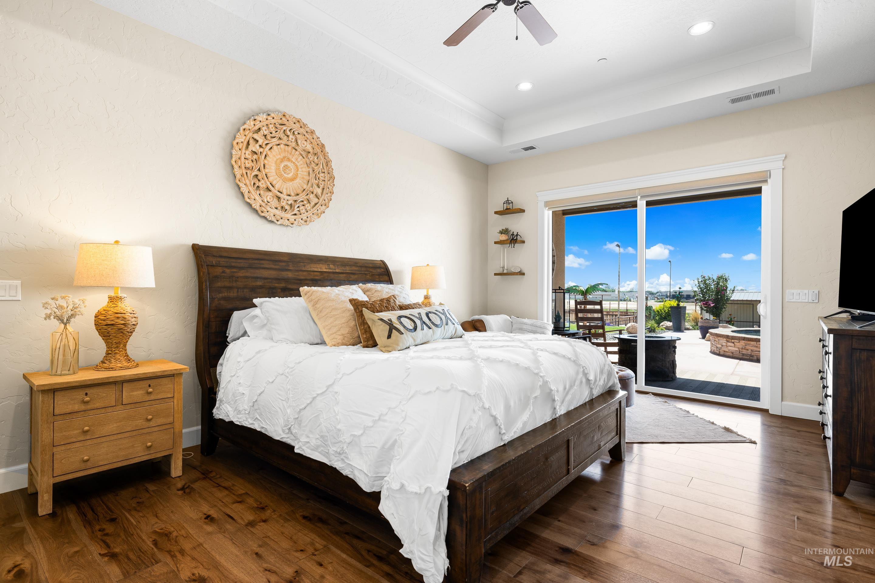 Bedroom featuring access to exterior, wood finished floors, a raised ceiling, a ceiling fan, and recessed lighting