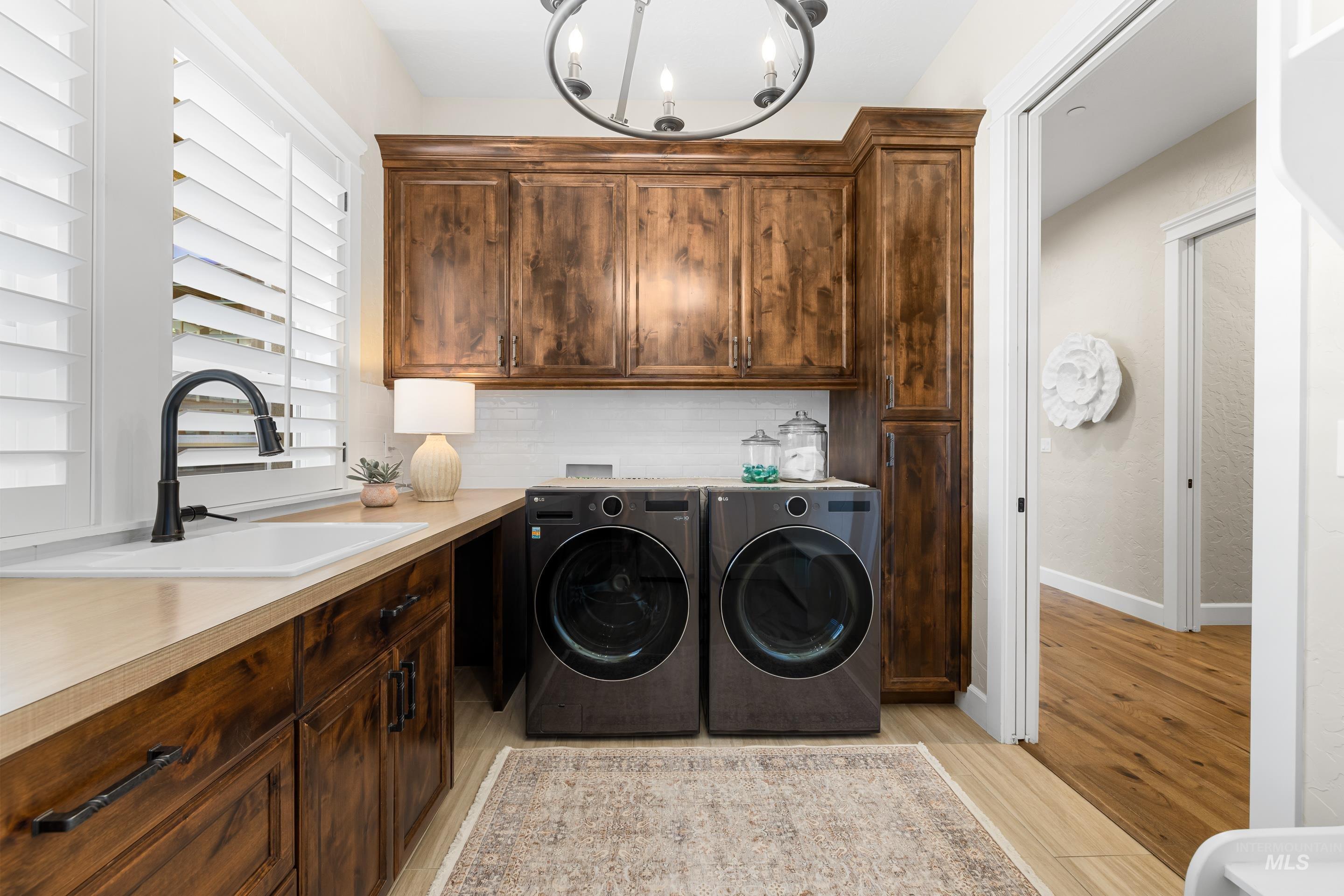 Laundry room featuring independent washer and dryer, cabinet space, a chandelier, and light wood finished floors