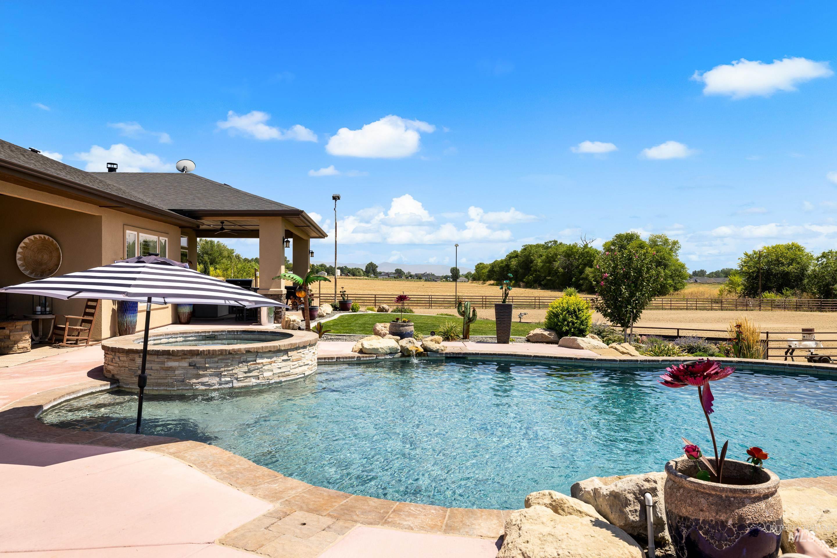 View of swimming pool with a patio, a pool with connected hot tub, and a view of rural / pastoral area