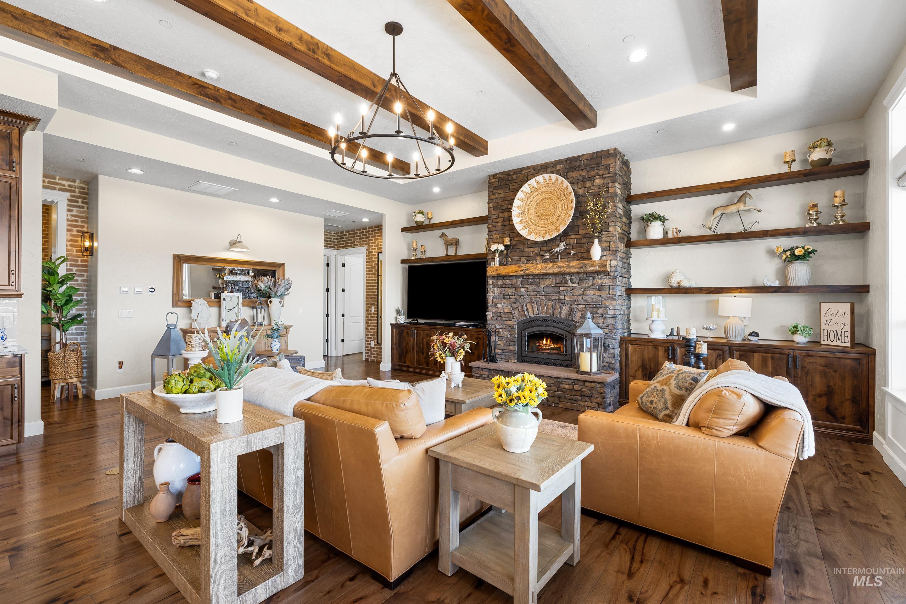 Living room with a fireplace, beamed ceiling, dark wood finished floors, recessed lighting, and a chandelier