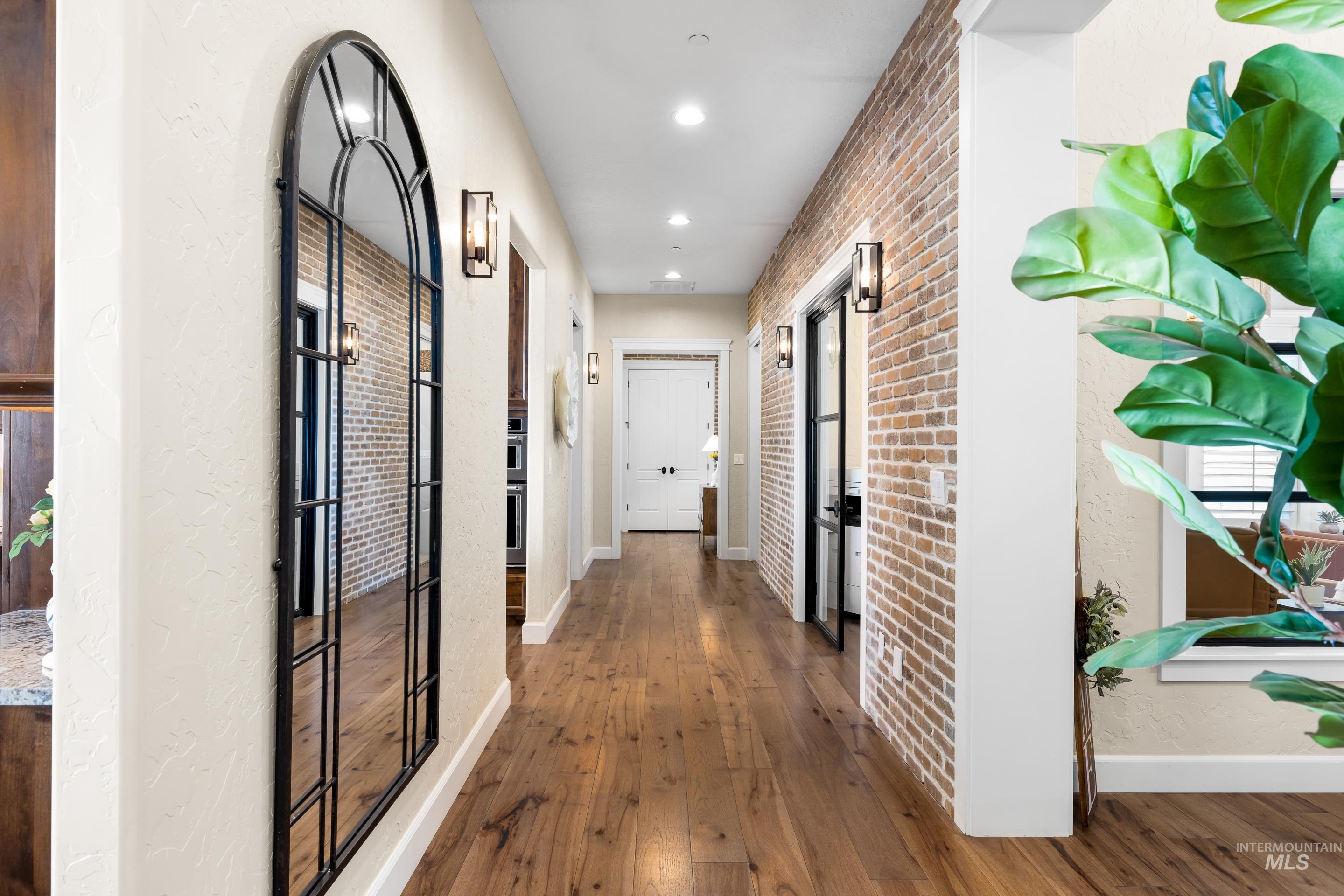 Hallway featuring hardwood / wood-style floors, recessed lighting, and brick wall
