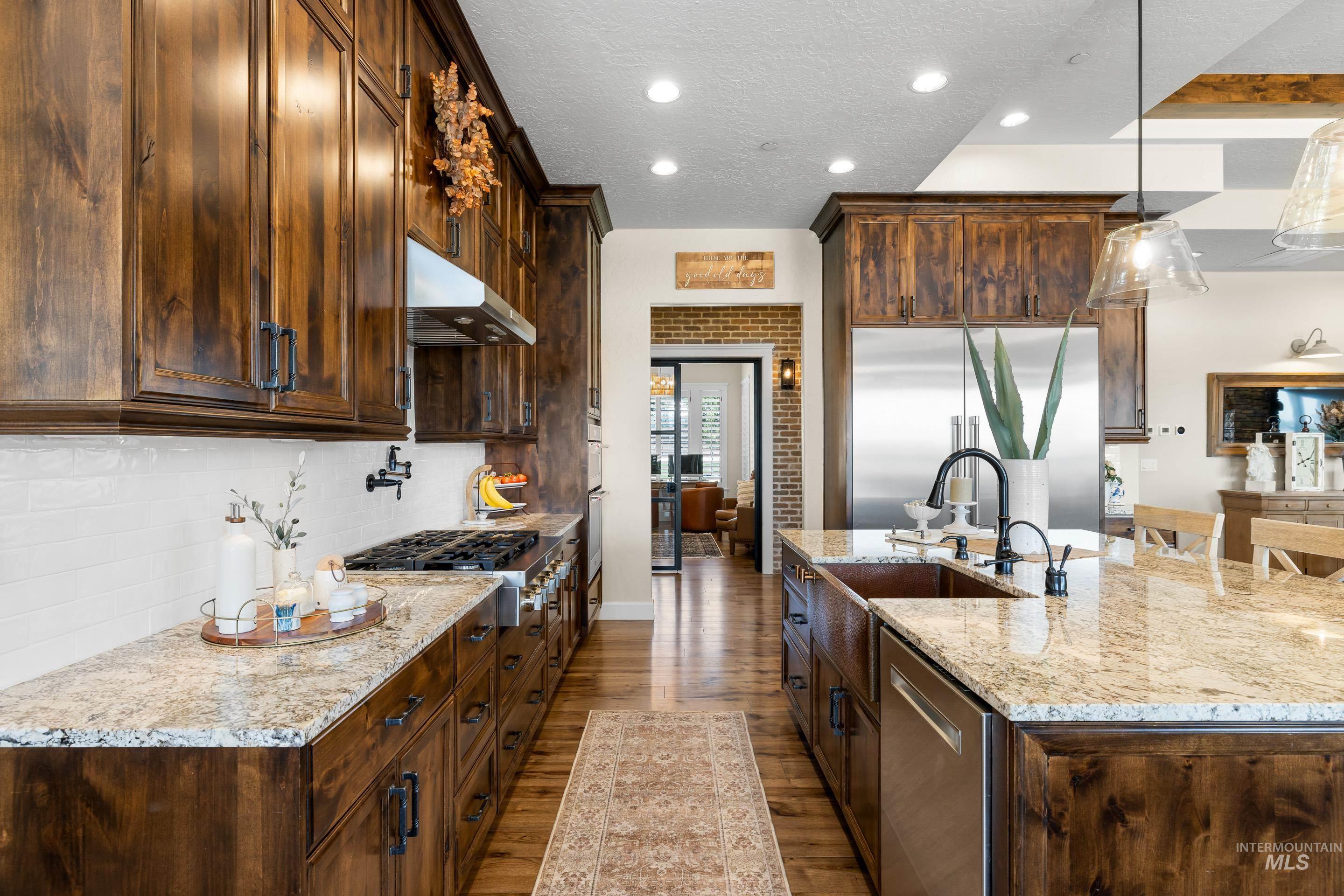 Kitchen with dark wood-style floors, recessed lighting, stainless steel appliances, a textured ceiling, and light stone counters