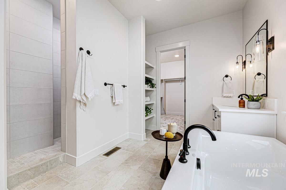Bathroom with vanity, a walk in closet, a freestanding bath, walk in shower, and recessed lighting
