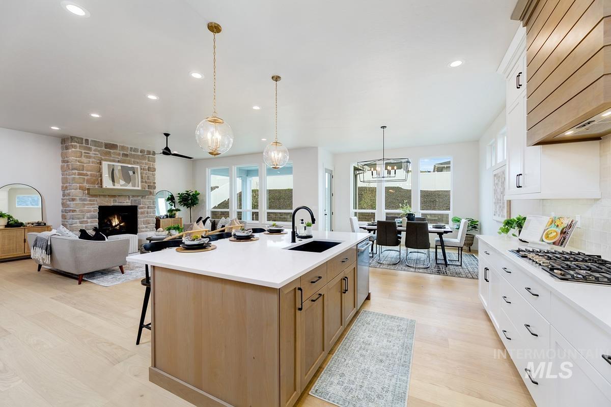 Kitchen featuring white cabinets, light wood-type flooring, a breakfast bar area, backsplash, and a large fireplace