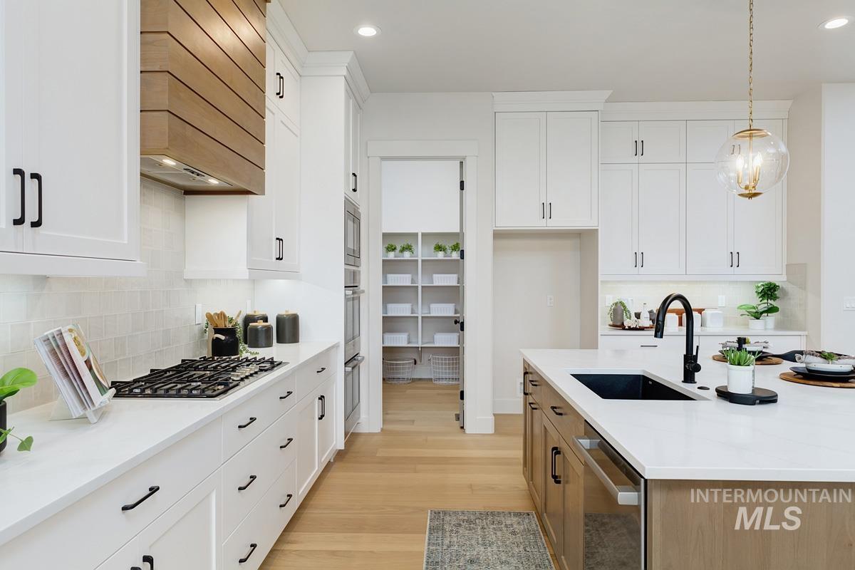 Kitchen featuring white cabinets, decorative backsplash, decorative light fixtures, light stone countertops, and recessed lighting