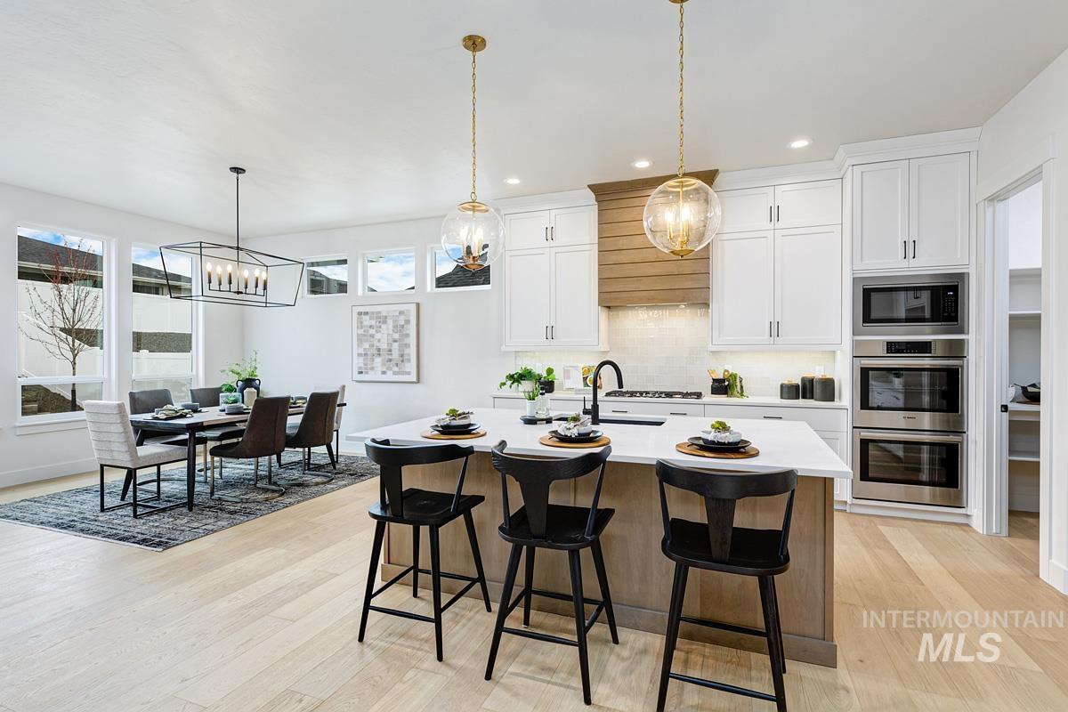 Kitchen with a breakfast bar, backsplash, white cabinets, plenty of natural light, and recessed lighting