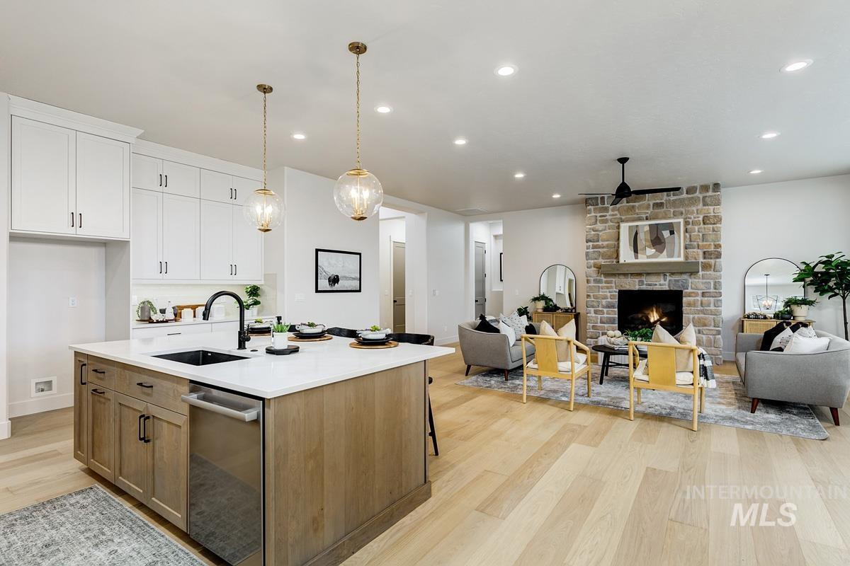 Kitchen with brown cabinets, open floor plan, light wood-style floors, decorative light fixtures, and recessed lighting